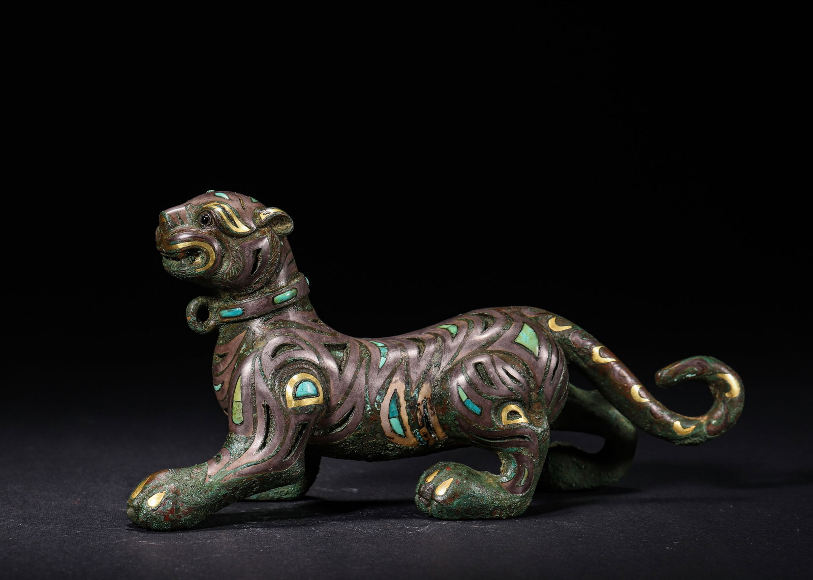 OPENWORK BRONZE TIGER WEIGHT INLAID WITH GOLD AND TURQUOISE, HAN DYNASTY (202 BC?C220 AD): L 17cm (6.69 in); W 6cm (2.36 in); H 8cm (3.15 in); Wt 1089g (2.401 lb),Bronze mat weight modelled as a striding tiger. It wears a collar with suspension ring. The body adopts openwork technique to fo
