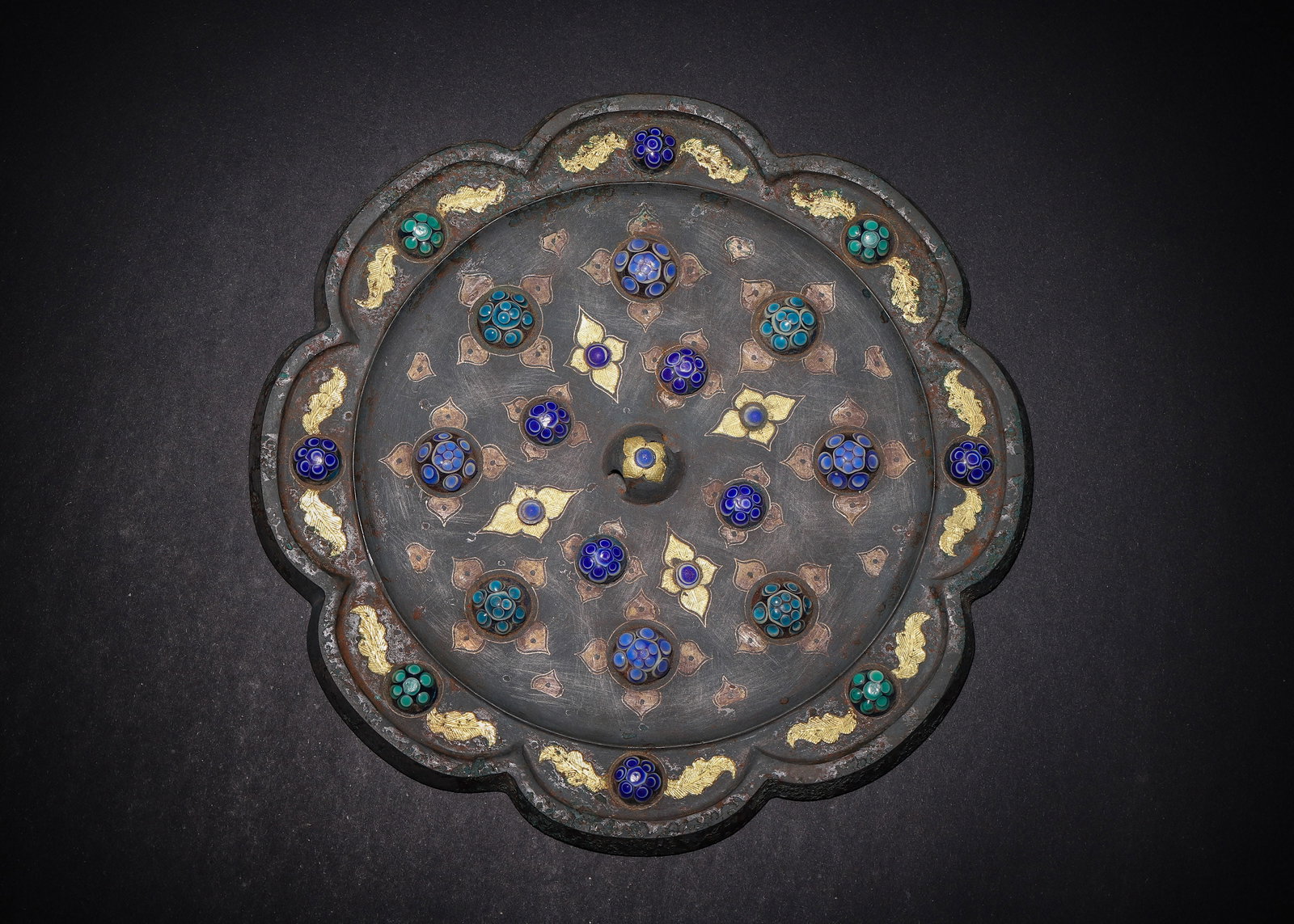 BRONZE LOBED MIRROR WITH GOLD & SILVER INLAY AND INLAID DRAGONFLY-EYE GLASS BEADS, HAN DYNASTY (202: D 20cm (7.87 in); Wt 1093g (2.41 lb),Lobed rim bronze mirror. The reverse is decorated with gold and silver inlaid foliage and feather motifs centred on a knob. Multiple blue and turquoise dragonfly-e