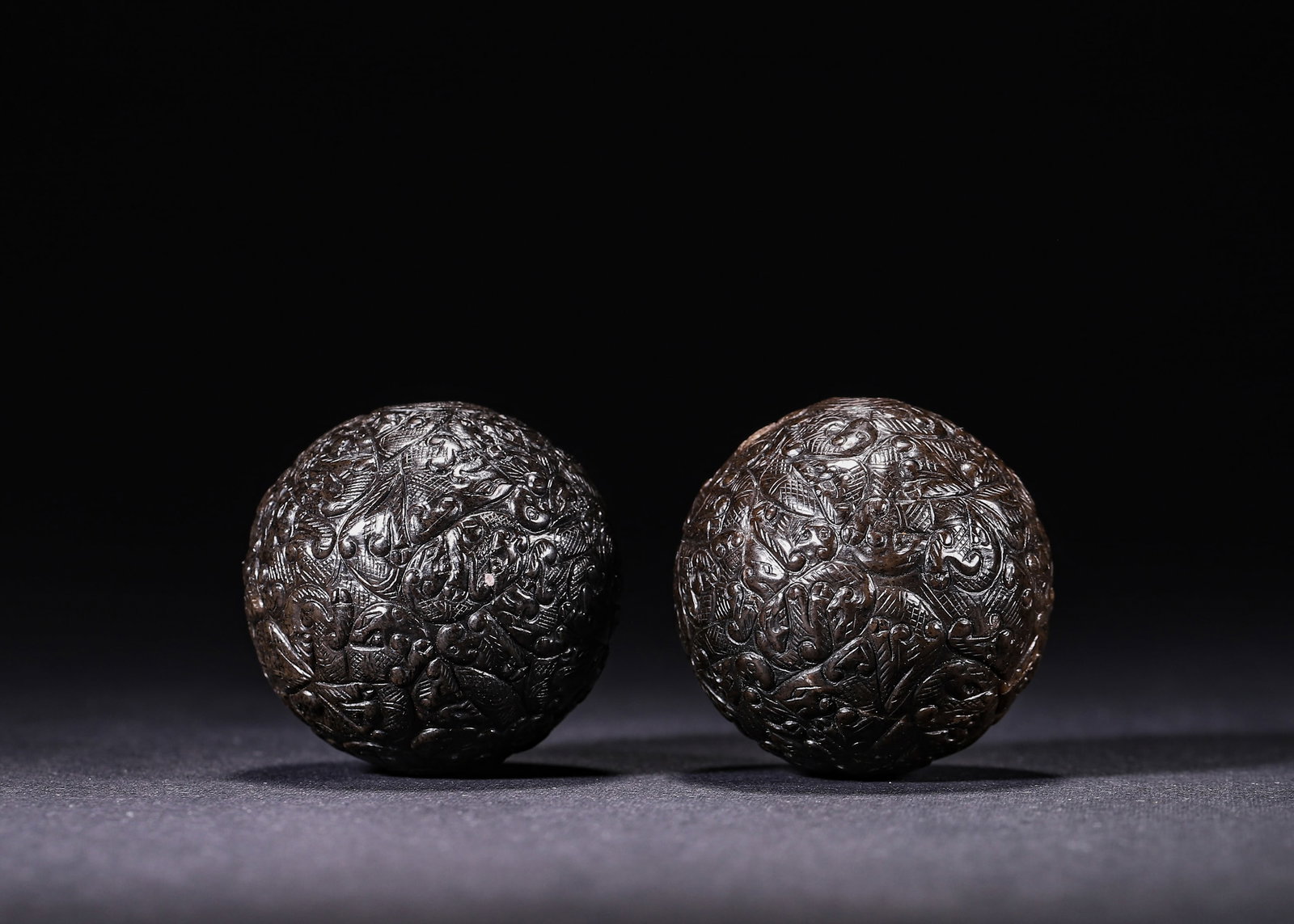 A PAIR OF HAN DYNASTY (206 BC-220 AD) CARVED JADE BALLS WITH CHILONG PATTERNS: Wt 173g (0.38 lb); D 4cm (1.57 in),A pair of jade spheres fully carved with interwoven chilong and cloud motifs. Fine incised lines cover the surface, with central perforations. The jade bears dark pa