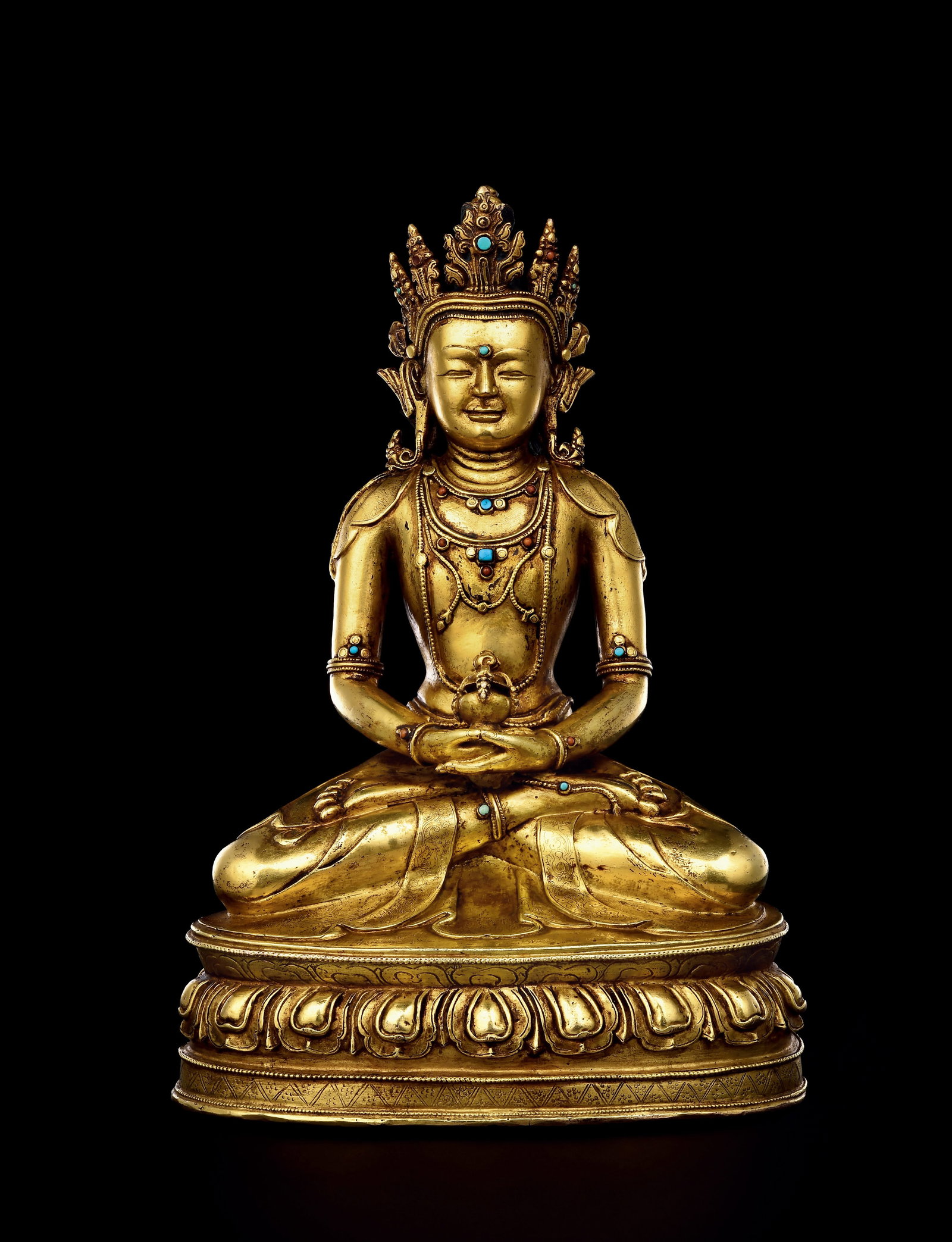GILT BRONZE SEATED AMITAYUS, 16TH CENTURY: H 29cm (11.42 in),Amitayus seated in padmasana on double lotus base. The archaic five-leaf crown accompanies a full, serene face. Ornate beaded jewellery inlaid with turquoise and coral adorns the bod