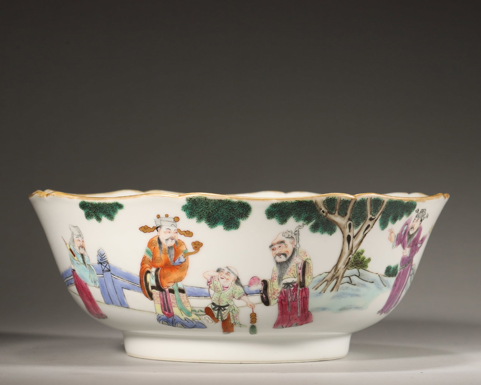 FAMILLE ROSE IMMORTALS LOBED BOWL, XIANFENG PERIOD, QING DYNASTY (1851-1861 AD): D 22cm (8.66 in); H 8.5cm (3.35 in),Lobed bowl with gilded rim, curved body and neatly shaped foot, bearing iron-red six-character seal mark "Da Qing Xian Feng Nian Zhi". Exterior fully decorated in f