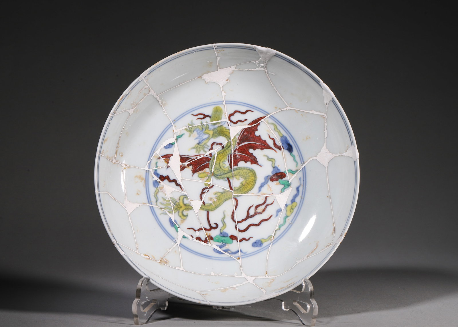 A DOUCAI WINGED DRAGON DISH, CHENGHUA PERIOD, MING DYNASTY: L 22cm (8.66 in); H 5.5cm (2.17 in),Ming Chenghua mark and period. Shallow porcelain dish with six-character reign mark in double blue circle on base. Central winged dragon among clouds, exterior drag