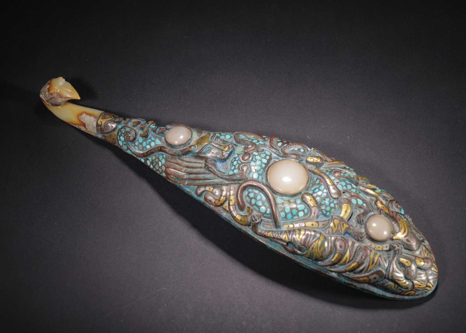LARGE BRONZE BELT HOOK WITH GOLD & SILVER INLAY, TURQUOISE AND JADE INLAY, WARRING STATES PERIOD: L 33cm (12.99 in); W 9cm (3.54 in); Wt 990g (2.18 lb),Massive cast bronze belt hook. The hook head is carved white jade phoenix. The body features high-relief dragons and mythical beasts, richly decor