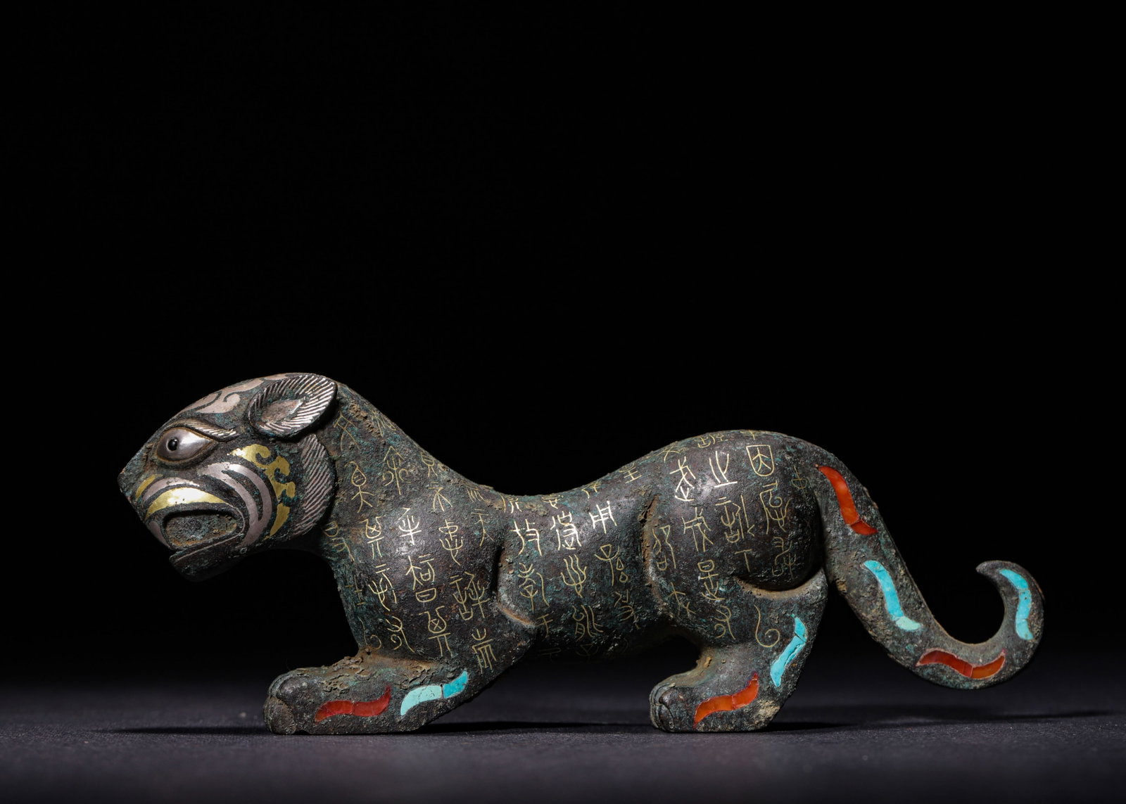 BRONZE TIGER TALLY INLAID WITH GOLD, SILVER, TURQUOISE AND AGATE, WARRING STATES PERIOD (475?C221: L 15cm (5.91 in); W 3cm (1.18 in); H 6cm (2.36 in); Wt 736g (1.62 lb),Bronze bipartite tiger tally modelled as a recumbent tiger. The facial features are decorated with inlaid gold and silver. The bod
