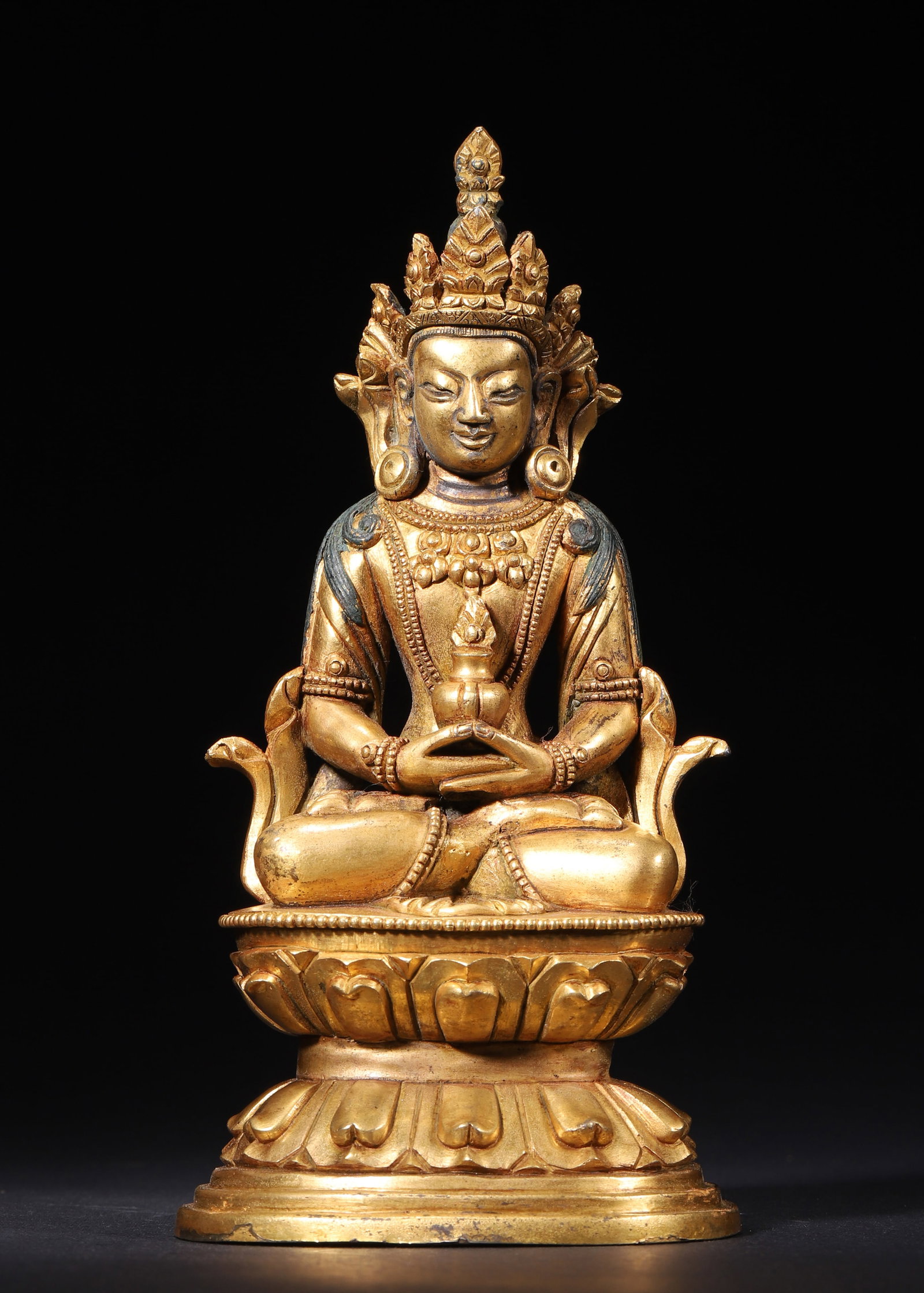 GILT BRONZE AMITAYUS SEATED FIGURE, QING DYNASTY (1644-1912 AD): L 9cm (3.54 in); W 7.5cm (2.95 in); H 18cm (7.09 in); Wt 734g (1.62 lb),Cast copper fully gilded. The deity wears a five-leaf crown with serene facial features. Seated in padmasana, hands cradling the