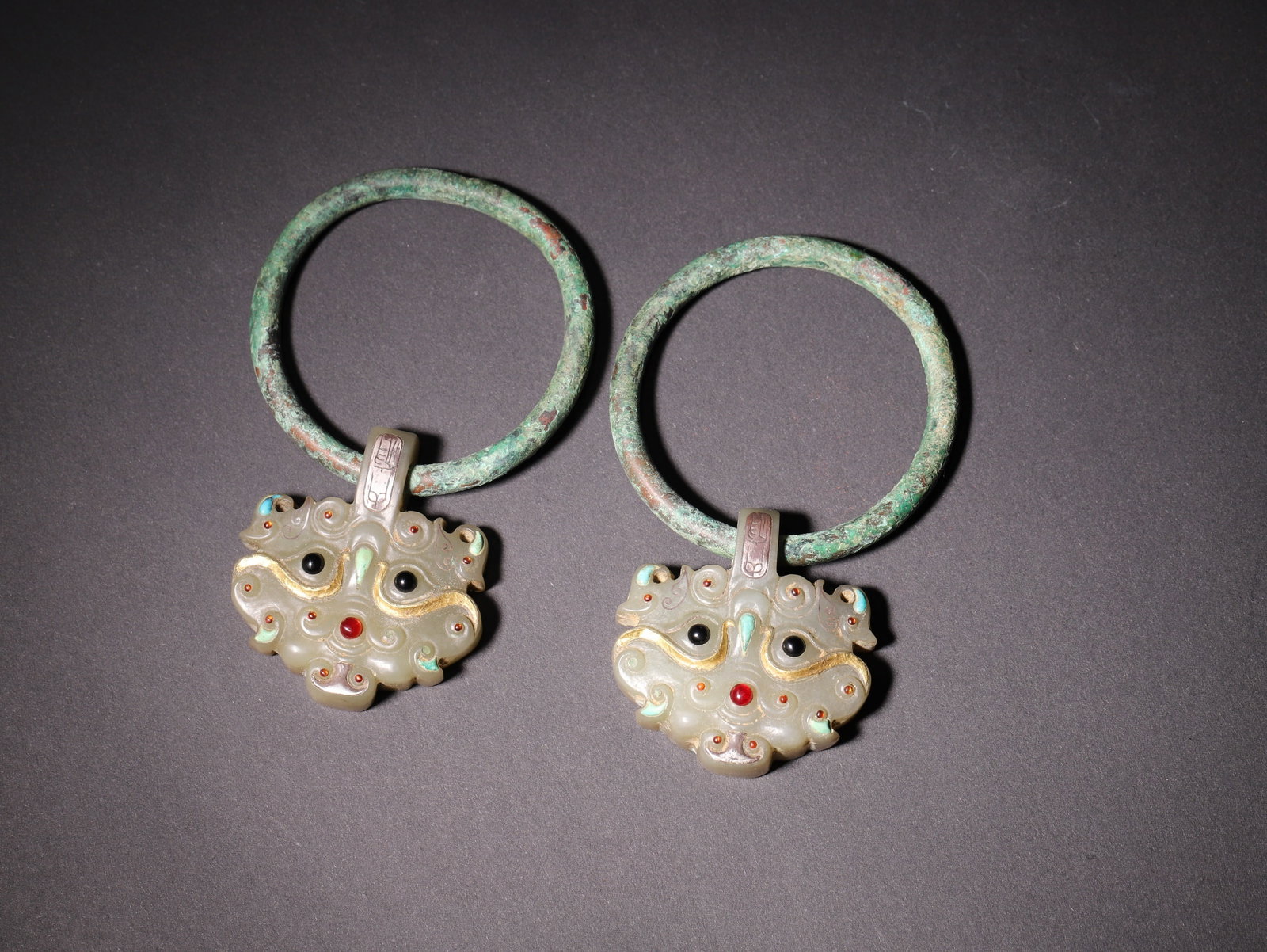 A Pair Of Hetian Jade Gold And Silver Inlaid Precious Stone Embellished Beast Faced Door Knockers,: L 10.0cm (3.94 in); W 6.2cm (2.44 in); Wt 122.0g (0.27 lb)A pair of Han Dynasty Hetian jade door knockers with gold and silver inlay and precious stone inlays. The jade beast faces are paired with pat