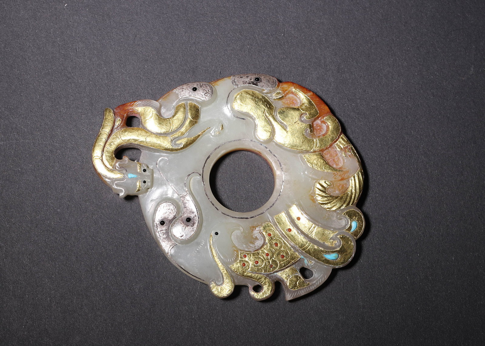 Hetian Jade Inlaid Gold & Silver Pendant With Dragon, Phoenix And Gemstones, Han Dynasty (202 Bc 220: L 8.60cm (3.39 in); W 7.20cm (2.83 in); Wt 67.00g (0.15 lb)Carved from white Hetian jade as an open outlined circular pendant with double sided decoration. Obverse inlaid with gold and silver depictin