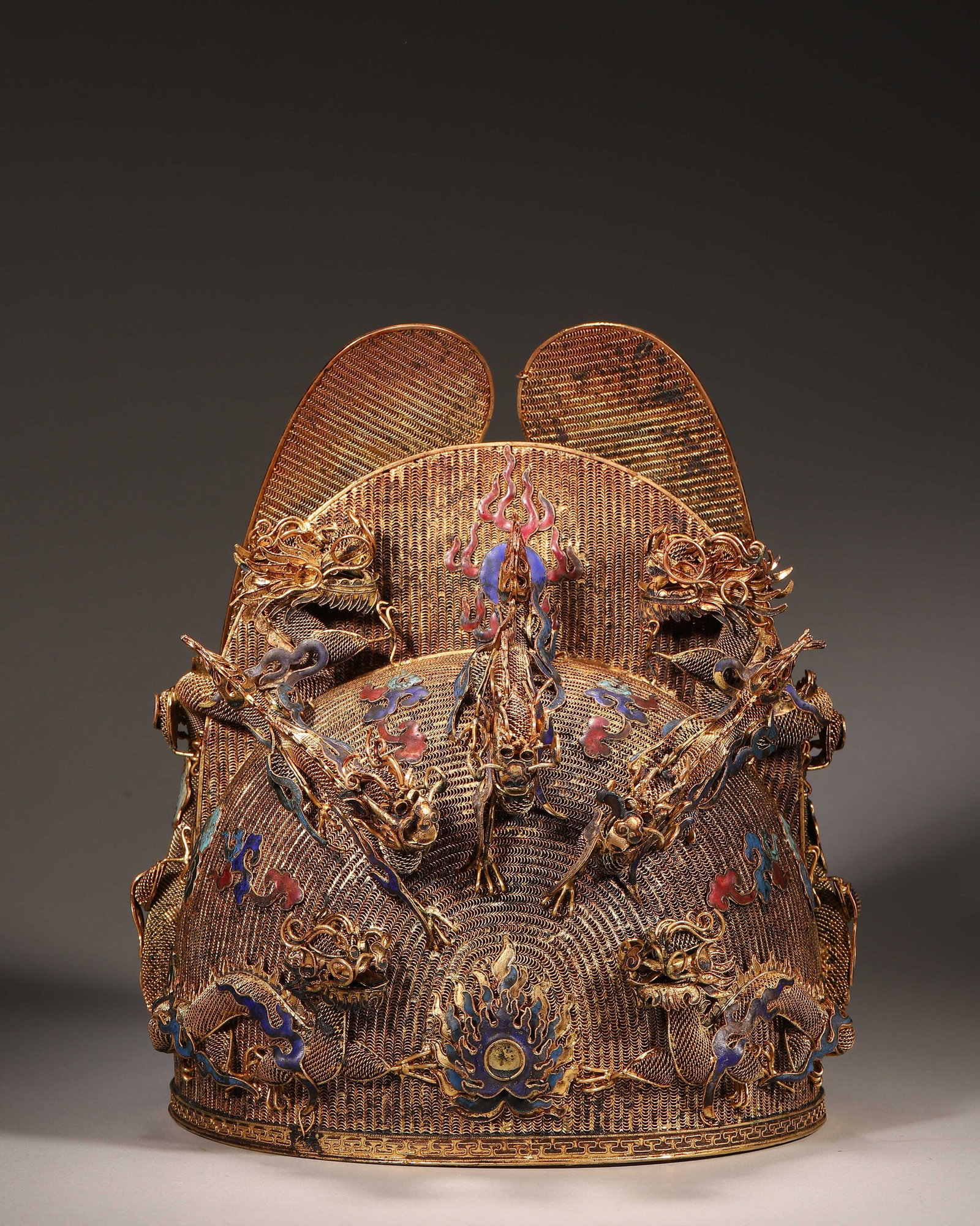Gilt Copper Filigree Enamel Nine Dragon Winged Crown, Qing Dynasty (1644 1912): Wt 1241g (2.74 lb); L 21cm (8.27 in); W 23cm (9.055 in); H 27cm (10.63 in)Gilt copper filigree nine dragon crown with enamel cloud and flame motifs. Twin rear wings engraved with dragons, exquisite fi