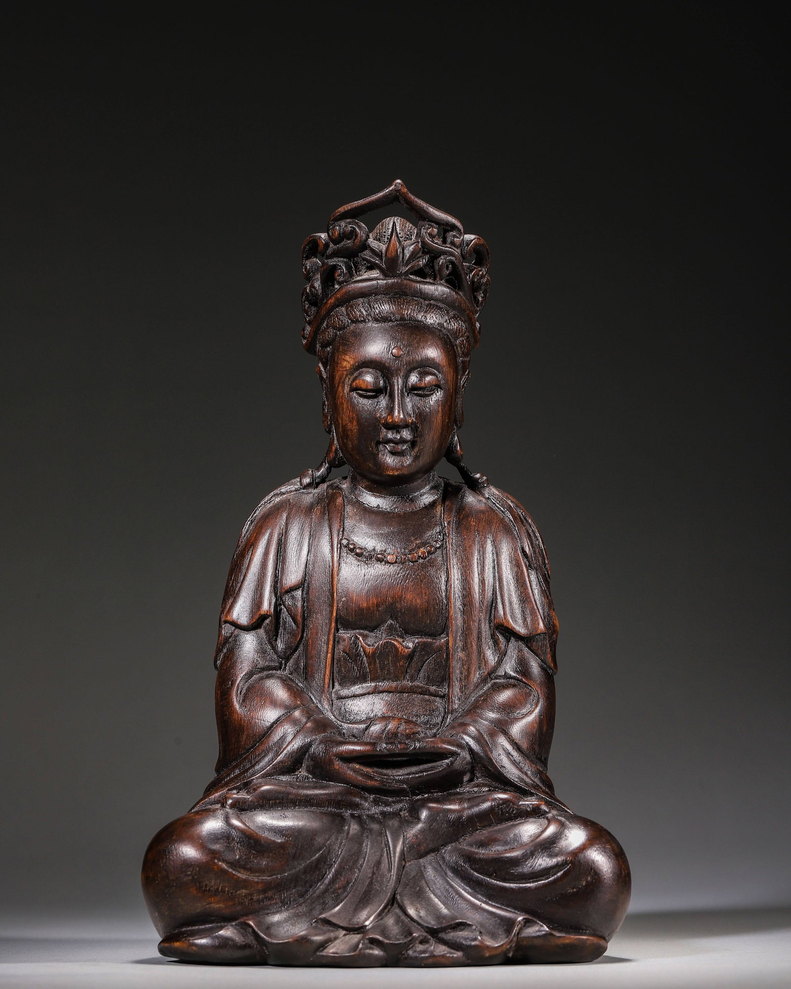 Carved Agarwood Seated Guanyin Statue Qing Dynasty: Wt 343g (0.76 lb); L 15cm (5.91 in); W 11cm (4.33 in); H 25cm (9.84 in)Carved from single agarwood block. Seated in lotus position, with openwork crown, serene facial features, beaded necklace, flowin