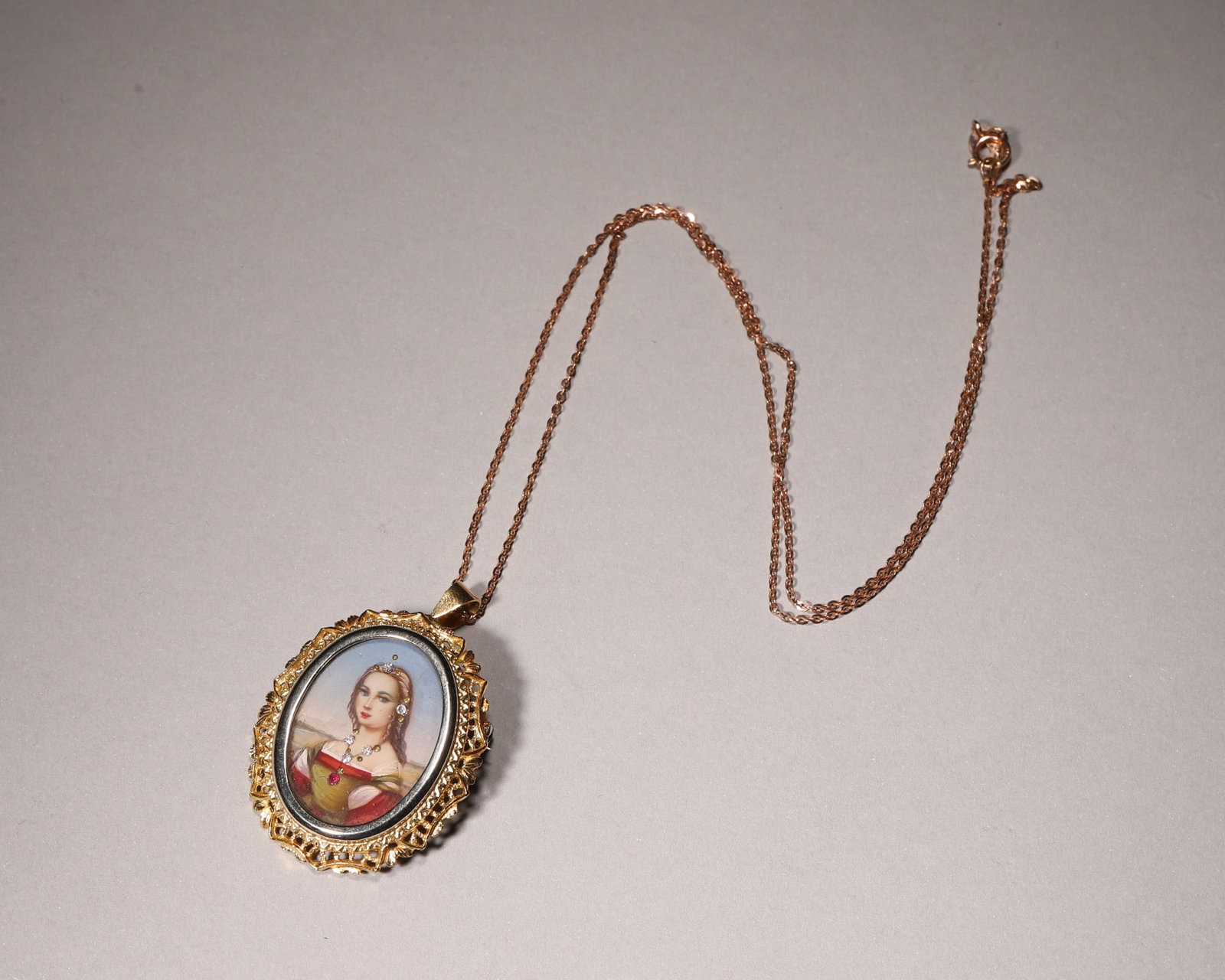 An 18K Gold Miniature Hand Painted Portrait Pendant: Wearable length 26 cm (10.24 in); Wt 8.2g (0.29 oz)This vintage European pendant is crafted of 18K gold with elaborate openwork leaf shaped gold frame. An oval panel features hand painted noble lady p