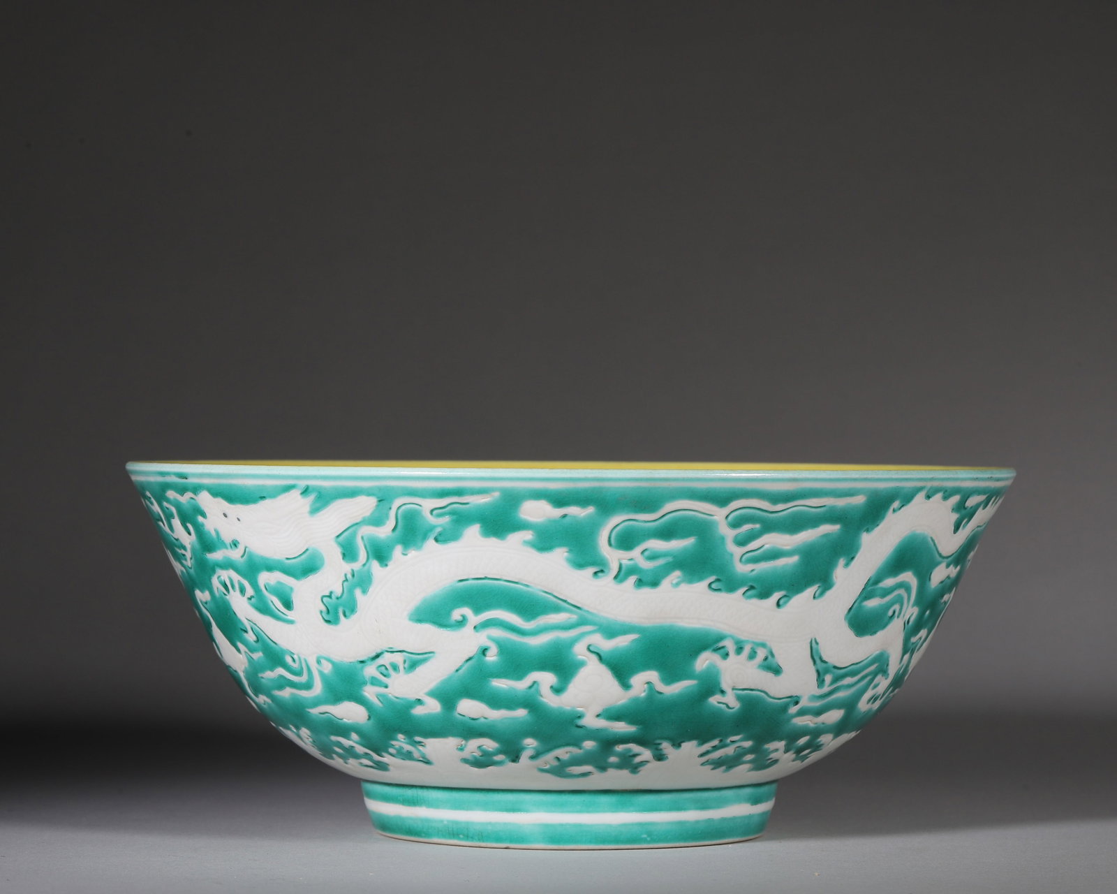 Yellowglazed Bowl, Green Reserved Dragon Motif, Hongzhi Ming Dynasty (14881505 Ce): W 19cm (7.48 in); H 8cm (3.15 in)Interior fully covered with yellow glaze. Exterior greenglazed ground reserved with white dragon amid clouds. Wellproportioned foot ring. Base bears sixcharacter Hongz