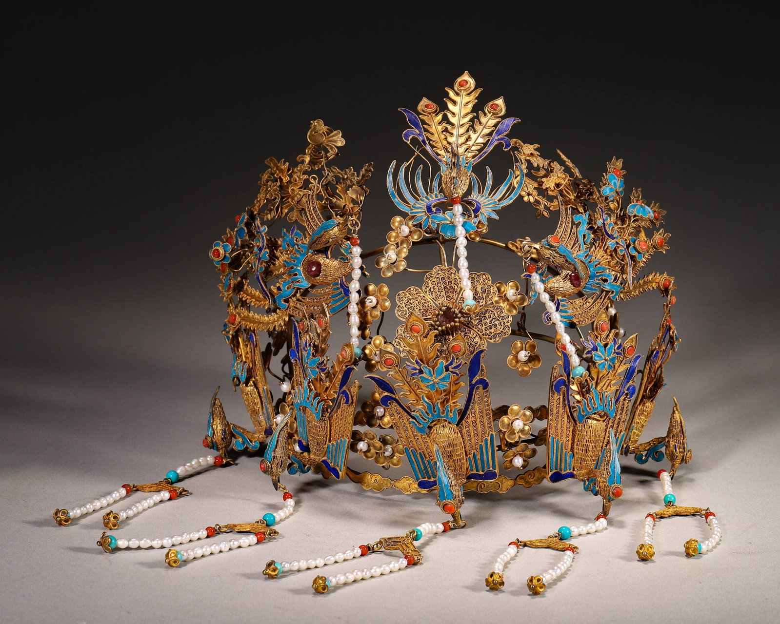 Silver Gilded Kingfisher Feather Phoenix Crown Inlaid With Pearl And Gemstone Qing Dynasty: Wt 257g (0.57 lb); L 16cm (6.299 in); W 11cm (4.33 in); H 14cm (5.51 in)Silver gilded filigree phoenix crown. Decorated with multiple phoenixes with kingfisher feather, inlaid pearls coral and turquoi