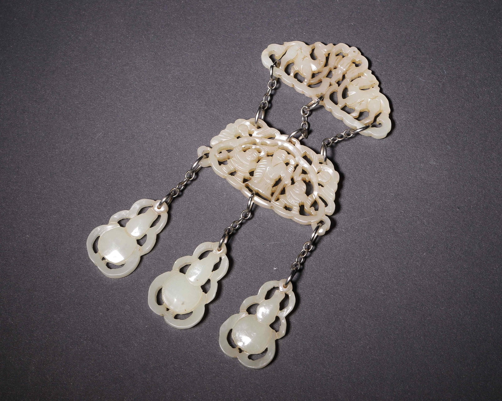 Openwork Nephrite Pendant With Interlocking Gourd Pendants, Qing Dynasty (1644 1912?Ce): Wt 43g (0.095 lb); Overall L 12cm (4.72 in); Overall W 6cm (2.36 in)White nephrite suite ornament. Two openwork plaques with figure and beast motifs linked by metal chains, suspending three interlocki