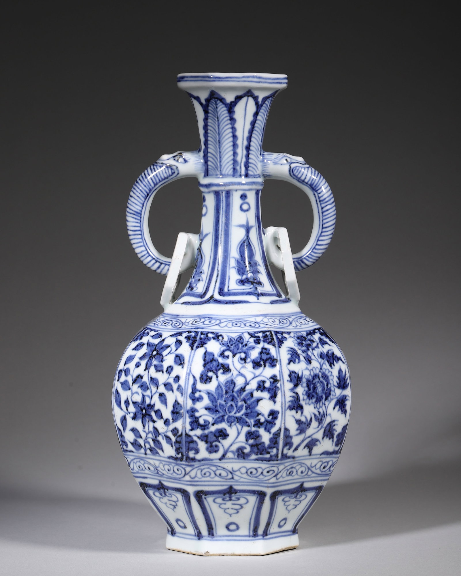 Blue And White Octagonal Vase With Dragon Loop Handles, Yuan Dynasty (12711368 Ce): W 14.5cm (5.71 in); H 30cm (11.81 in)Octagonal porcelain vase with dragonhead movable loop handles. Painted with scrolling seasonal flowers, plantain leaves and lotus panels. Vivid cobalt blue tone. U