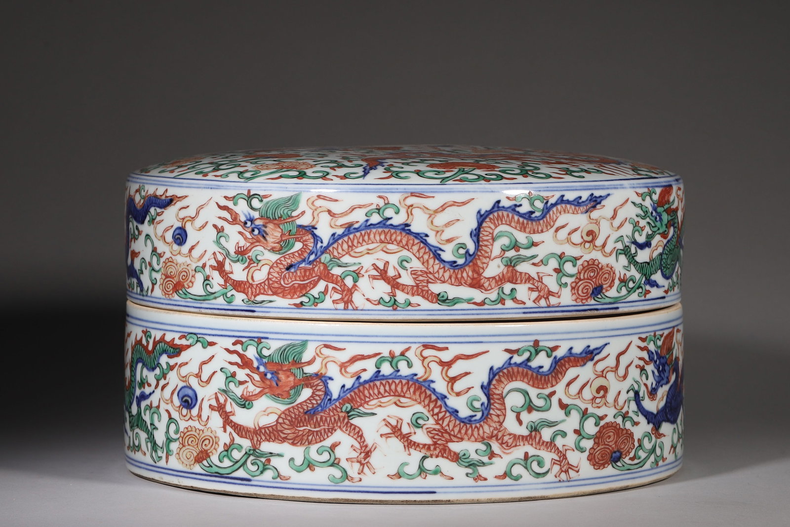 Wucai Dragon Pattern Covered Box, Wanli Period Ming Dynasty (15731620 Ce): L 27.5cm (10.83 in); H 14cm (5.51 in)Cylindrical covered box with fitted mouth. Cover top painted with multiple wucai dragons amid scrolling flowers. Outer wall decorated with striding dragons, flames