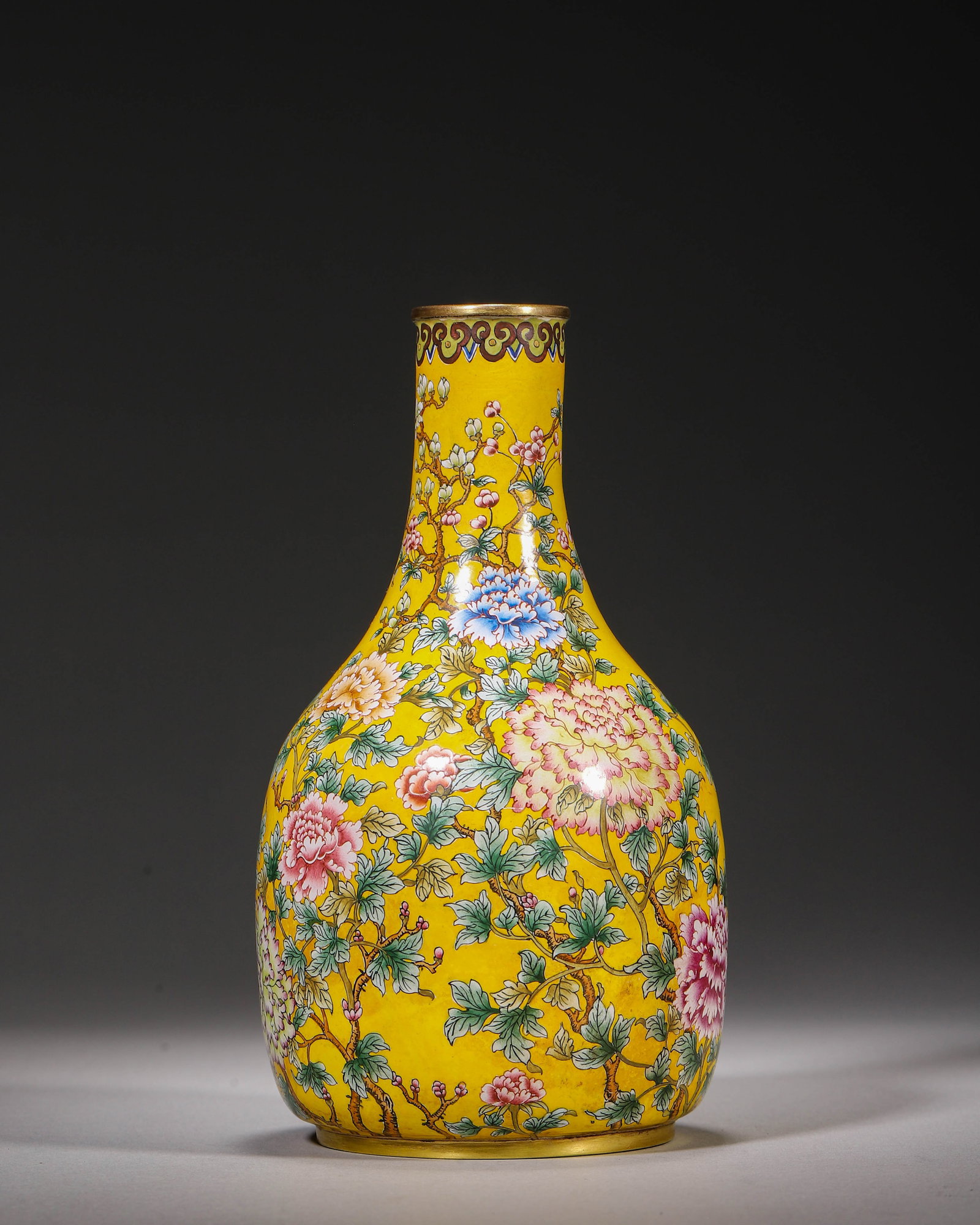 Copper Body Painted Enamel Vase With Peony Decoration On Yellow Ground, Qianlong Period, Qing: W 7cm (2.76 in); H 15cm (5.91 in)Gilt rimmed copper body painted enamel vase with long neck and bulbous body. Bright yellow ground fully decorated with colourful peonies. Key fret band beneath rim. Fo