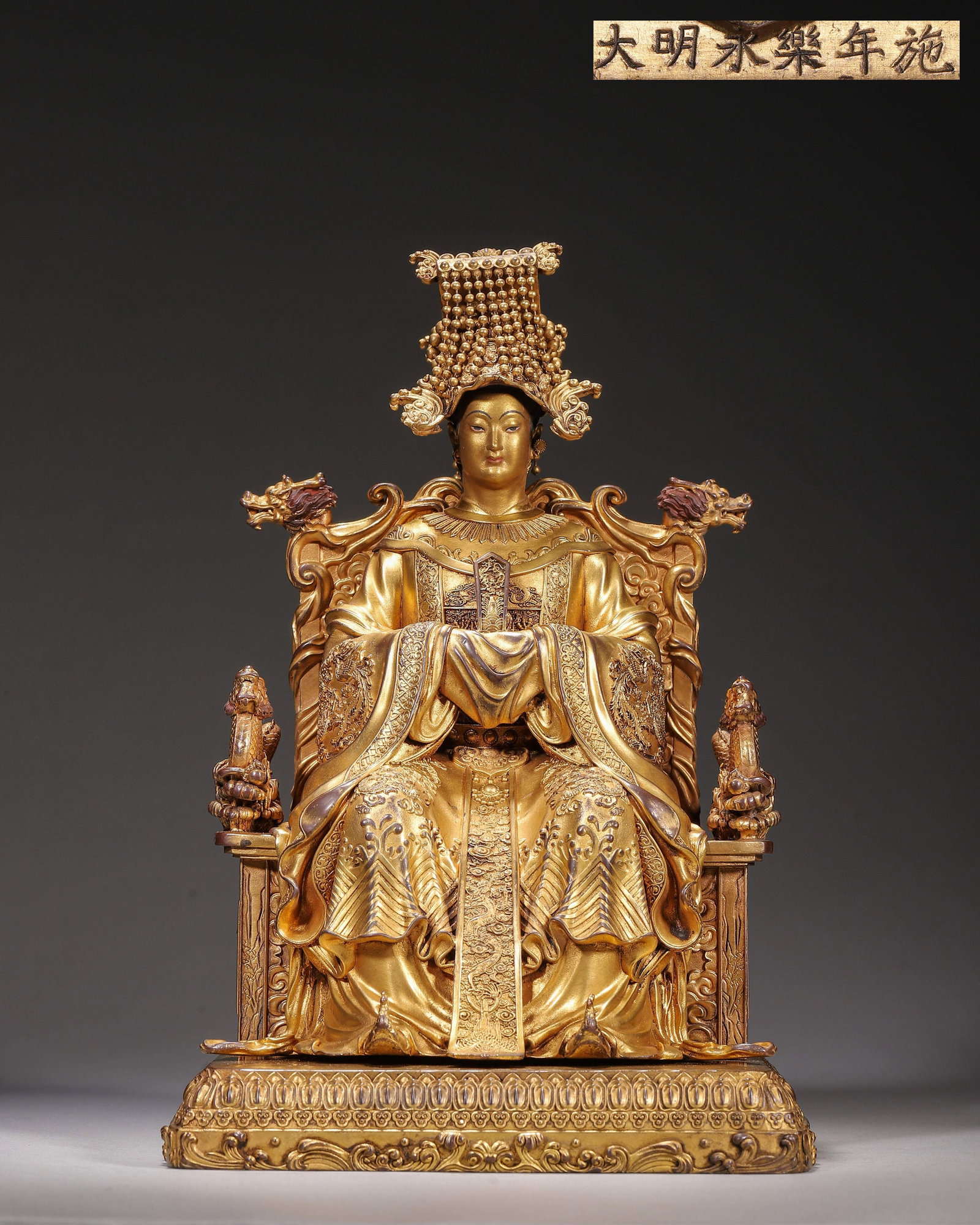 Gilt Bronze Seated Statue Of Mazu, Imperial Court Made,Inscribed "Made In Yongle Reign Of Great: Wt 2727g (6.012 lb),L 15cm (5.91 in),W 15cm (5.91 in),H 25cm (9.84 in)Imperial court made.The statue depicts Mazu seated formally, adorned with a pearl studded nine streamed imperial crown. Her facial