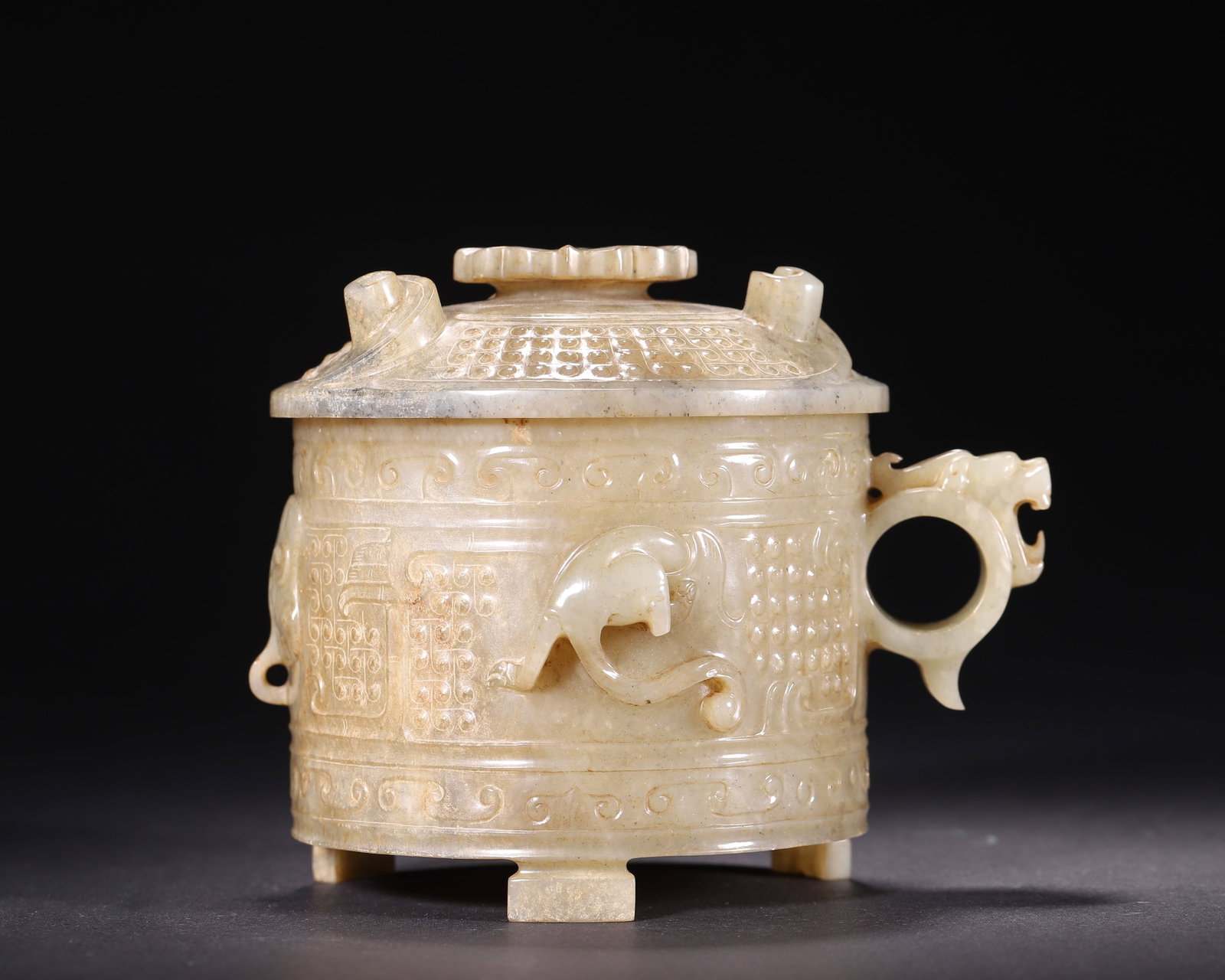 Hetian Jade Zhi Vessel With Relief Chilong And Beast Mask, Han Dynasty, 202B.C. 220A.D.: Wt 482g (1.063 lb); L 14cm (5.51 in); W 12cm (4.72 in); H 11cm (4.33 in)Hetian jade covered with earth and yellowish brown patina. Cylindrical body with flower shaped knob cover, dragon head ring hand