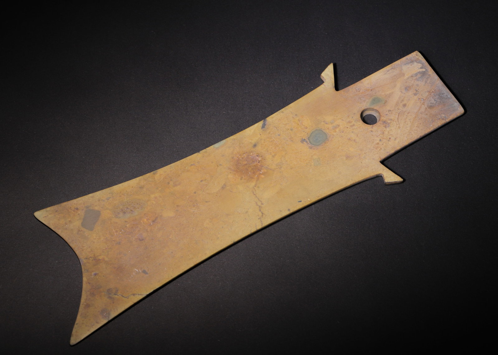 Archaic Jade Zhang Blade, Shang Dynasty (C.1600 1046 Bc): L 27cm (10.63 in); W 8.5cm (3.35 in); Wt 212g (0.47 lb)The jade is entirely suffused with yellowish brown burial patina, retaining natural mineral speckles across the surface. Elongated flat form, fin