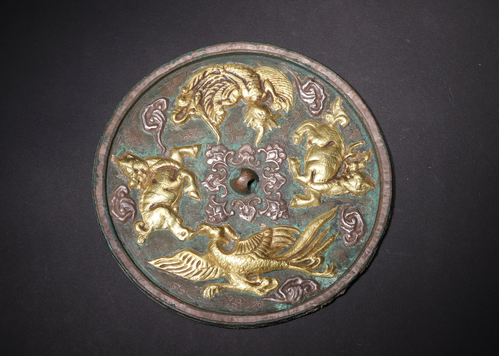 Tang Dynasty Bronze Mirror With Gilded & Silver Inlaid Four Divine Creatures: D 15.50cm (6.10 in); Wt 493.00g (1.09 lb)Round Tang bronze mirror with hemispherical knob. The reverse features high relief divine beasts: twin phoenixes, celestial deer and tortoise, crafted with com