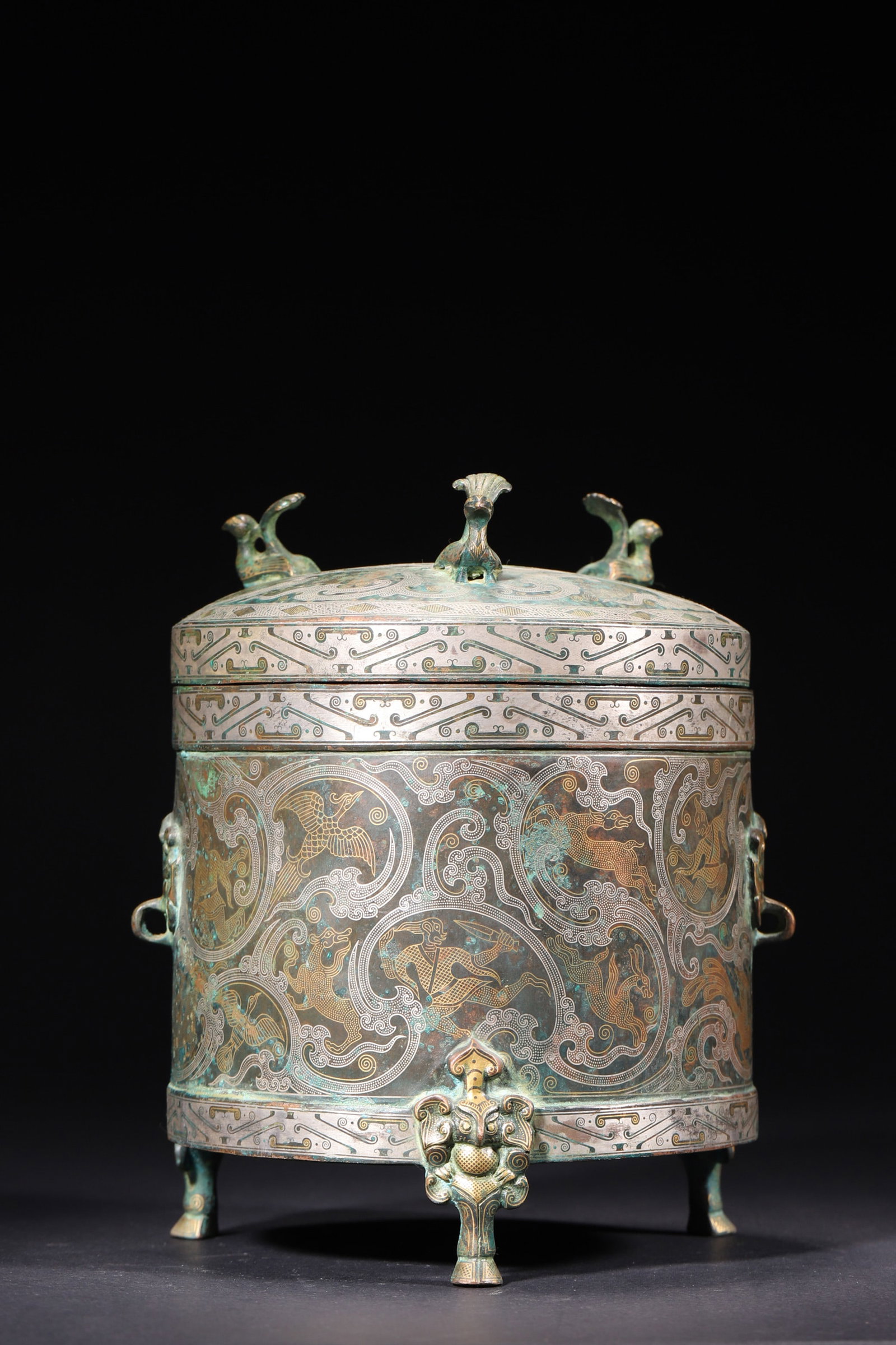 A Gold And Silver Inlaid Bronze Tripod Casket With Auspicious Beast Pattern Warring States Period: Diameter 15.0cm (5.91in), Height 19.0cm (7.48in), Weight 2308.0g (5.09lb)This Warring States bronze tripod casket is decorated with gold and silver inlaid hunting and beast patterns. It has a bird kno