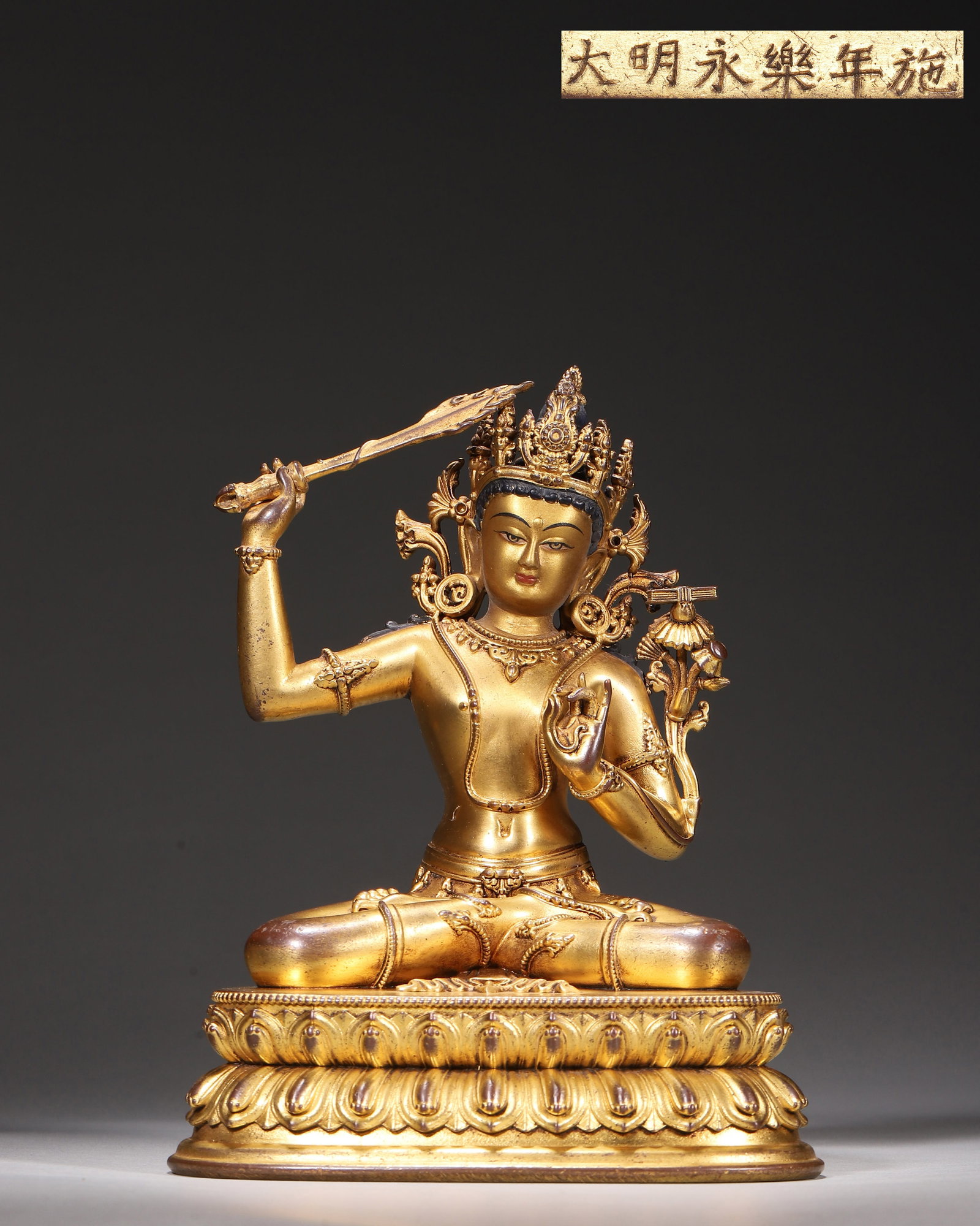 Gilt Bronze Seated Manjushri, Imperial Court Made,Marked "Made In Yongle Reign Of Great Ming",: Wt 839g (1.85 lb),L 12cm (4.72 in),W 10cm (3.94 in),H 16cm (6.299 in)Imperial court made.The Bodhisattva sits in padmasana with crown. Right hand holds wisdom sword, left hand grasps lotus stem with s