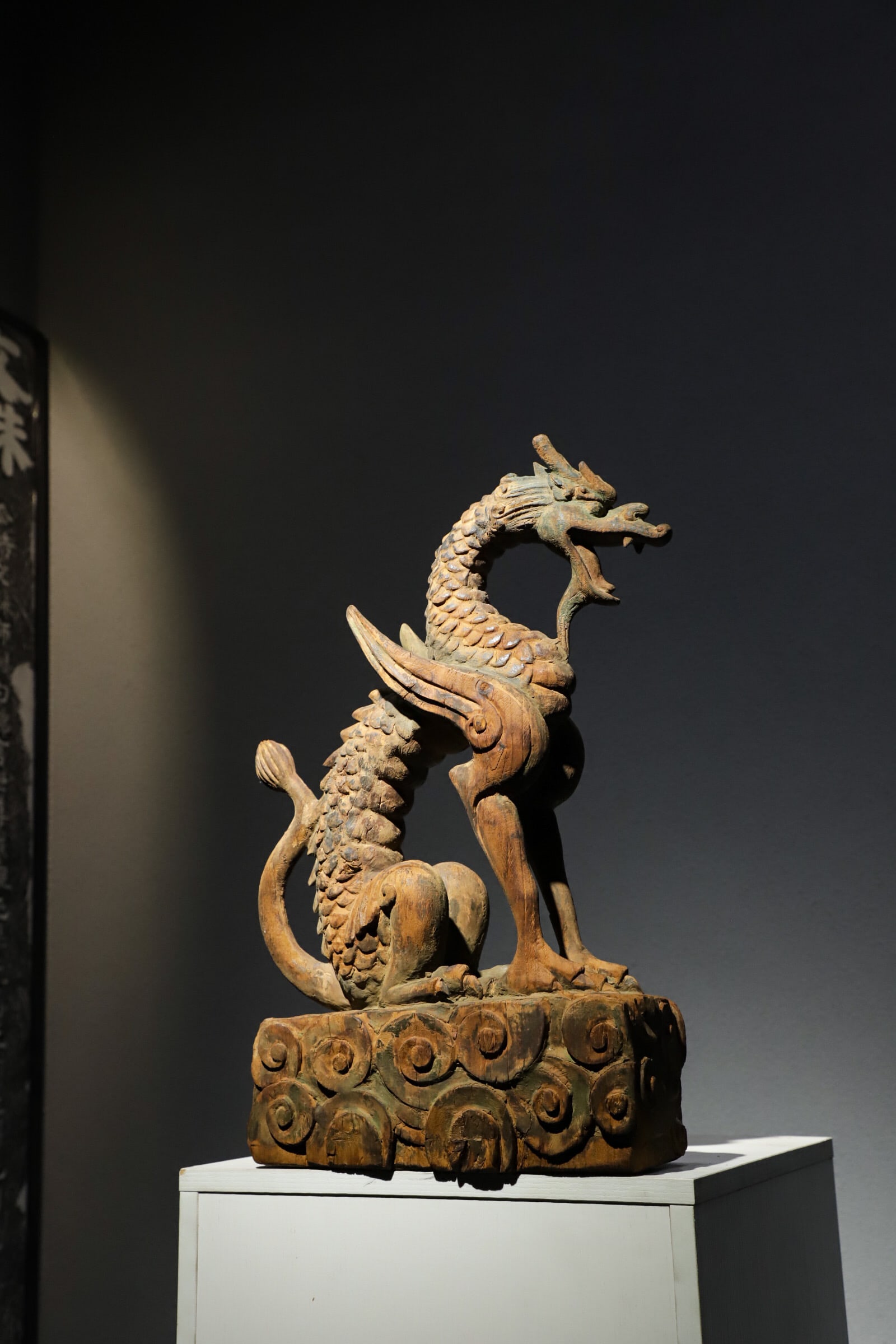 Carved Wood Winged Dragon Ornament, Song Dynasty (960 1279): H 54cm (21.26 in); L 32cm (12.598 in); W 13cm (5.12 in)Carved from single wood block. Coiled winged dragon with detailed scales, head raised open mouthed. Base fully carved with cloud patterns. Origin