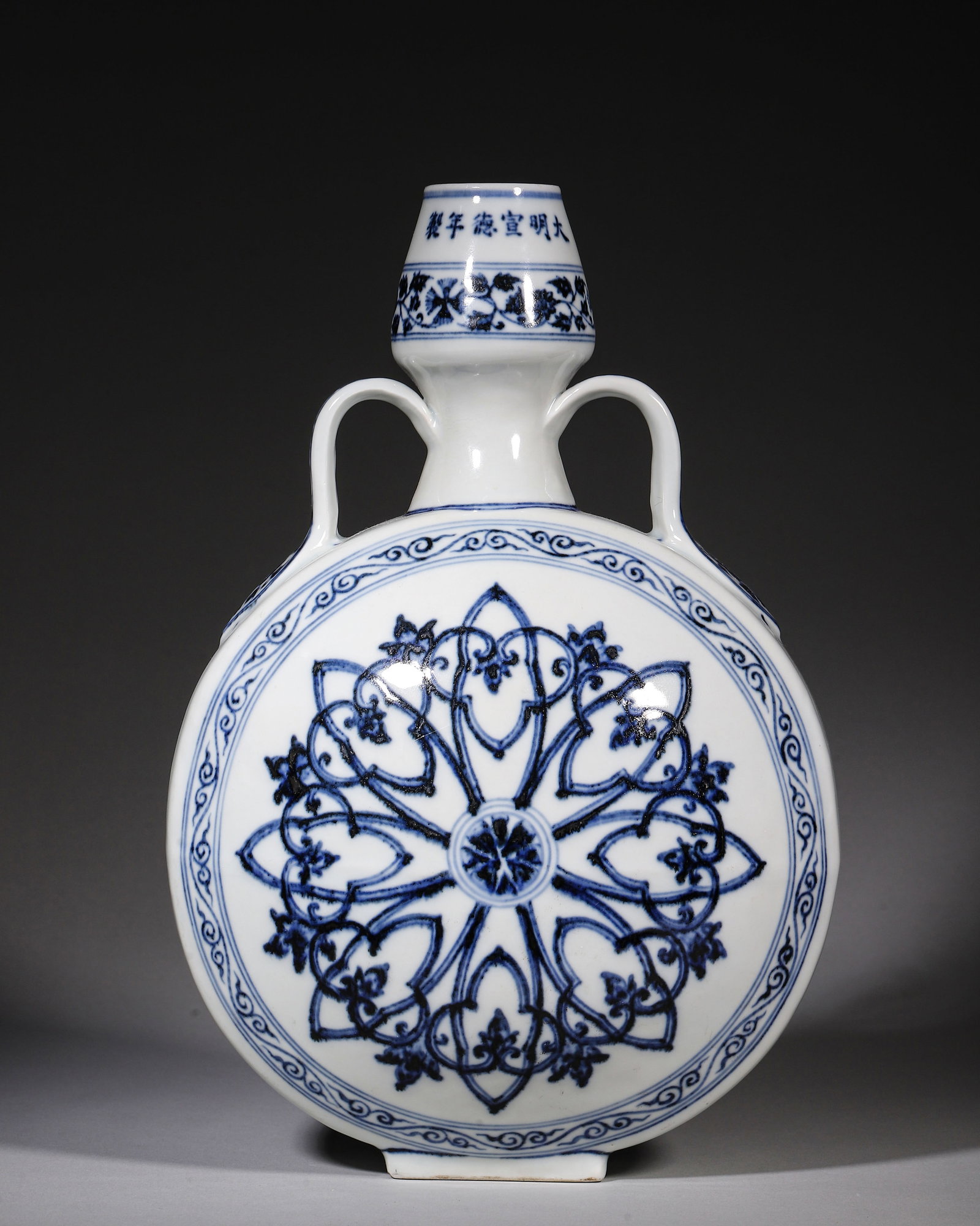 Blue And White Moonshaped Vase With Ribbon Handles, Xuande Period Ming Dynasty (14261435 Ce): W 20cm (7.87 in); H 29cm (11.42 in)Garlicshape neck with ribbon handles, flattened moonshaped body, square foot. Inscribed Xuande reign mark. Both sides painted with rosette medallion, scrolling flora