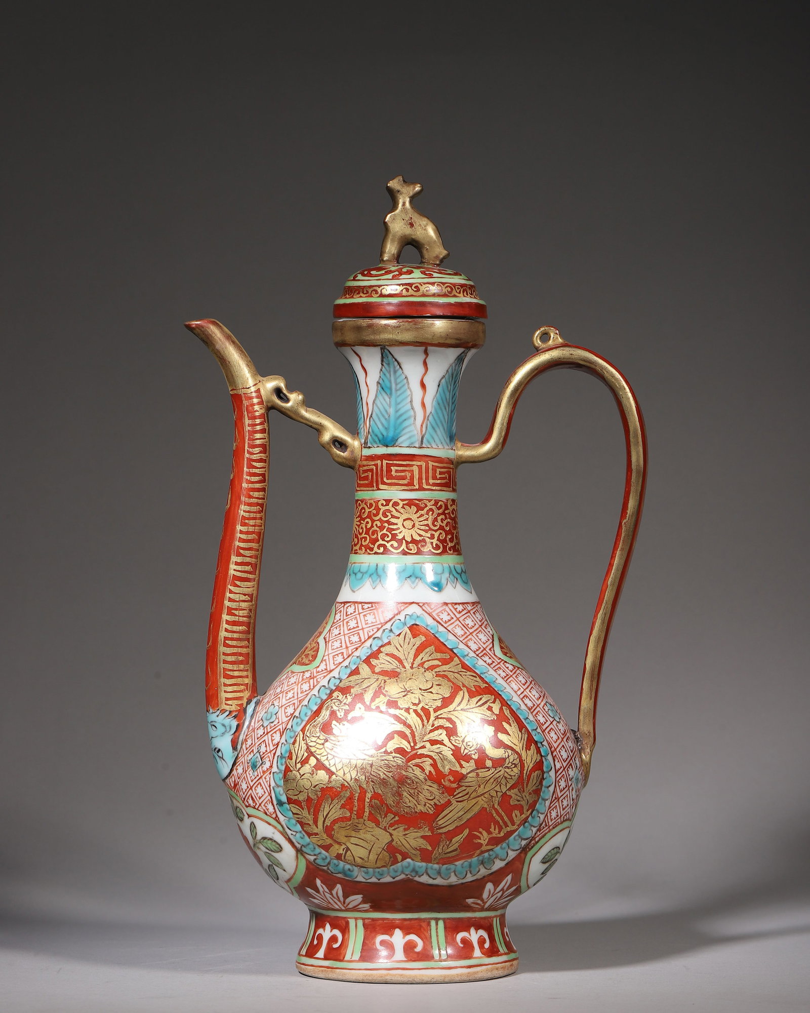 Wucai Gilt Ewer With Bird And Flower Motifs, Jiajing Period Ming Dynasty (15221566 Ce): W 18cm (7.087 in); H 31cm (12.205 in)Ewer with beastknob cover, long spout and curved handle. Pearshaped body and ring foot. Overall wucai gilt decoration. Gilt birdandflower panels, banana leaf, keyf