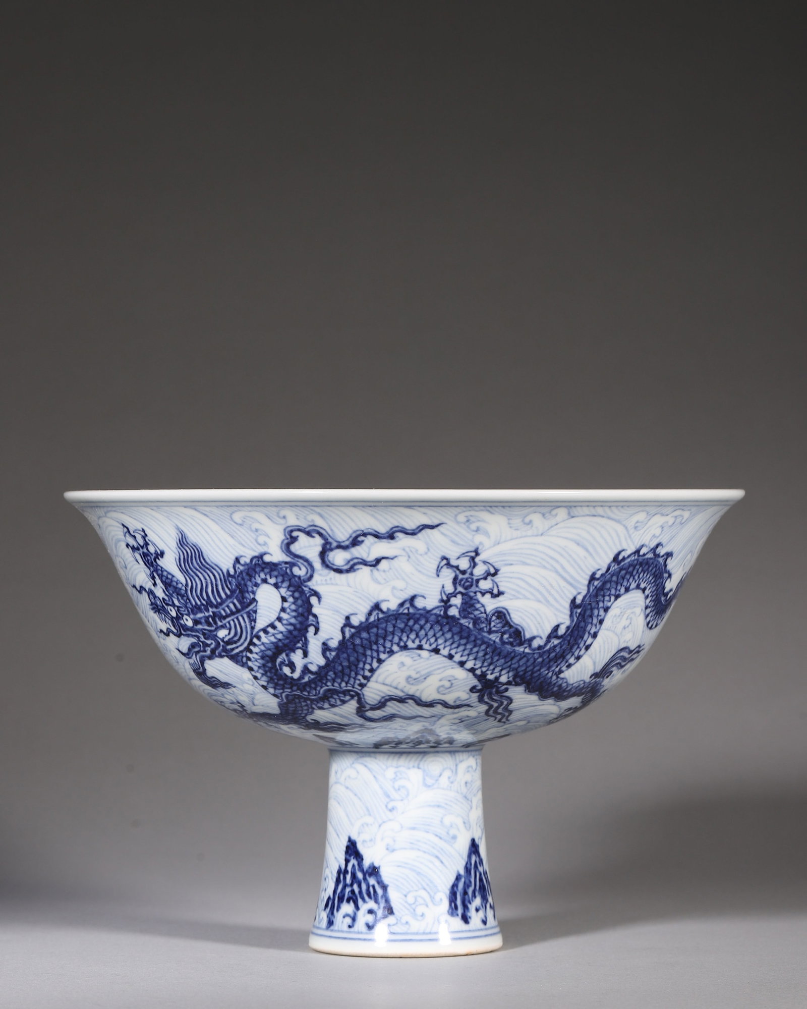 Blue And White Stem Bowl With Dragon And Sea Wave, Xuande Ming Dynasty (14261435 Ce): W 17cm (6.69 in); H 11cm (4.33 in)Stem bowl. Exterior painted with dragons amid surging sea waves. Stem decorated with waves and rocky mountains. Bowl centre bears sixcharacter Xuande reign mark withi