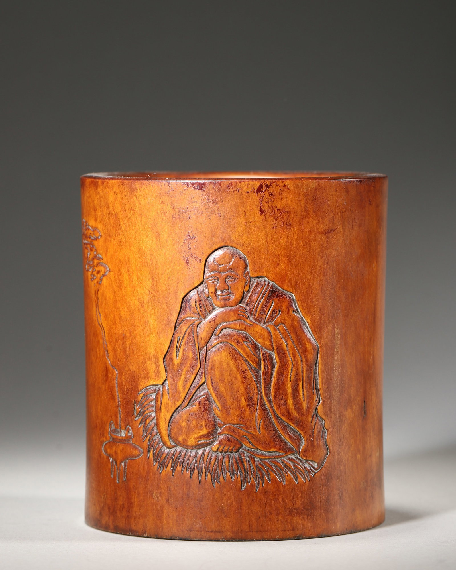 Boxwood Brush Pot Carved With Luohan And Poem (Qing Dynasty,1644 1912): Wt 311g (0.6856 lb); D 9.5cm (3.7402 in); H 10.5cm (4.1339 in)Solid boxwood brush pot. One side relief carved seated luohan with incense burner. Reverse incised Diamond Sutra verse with signature Qing