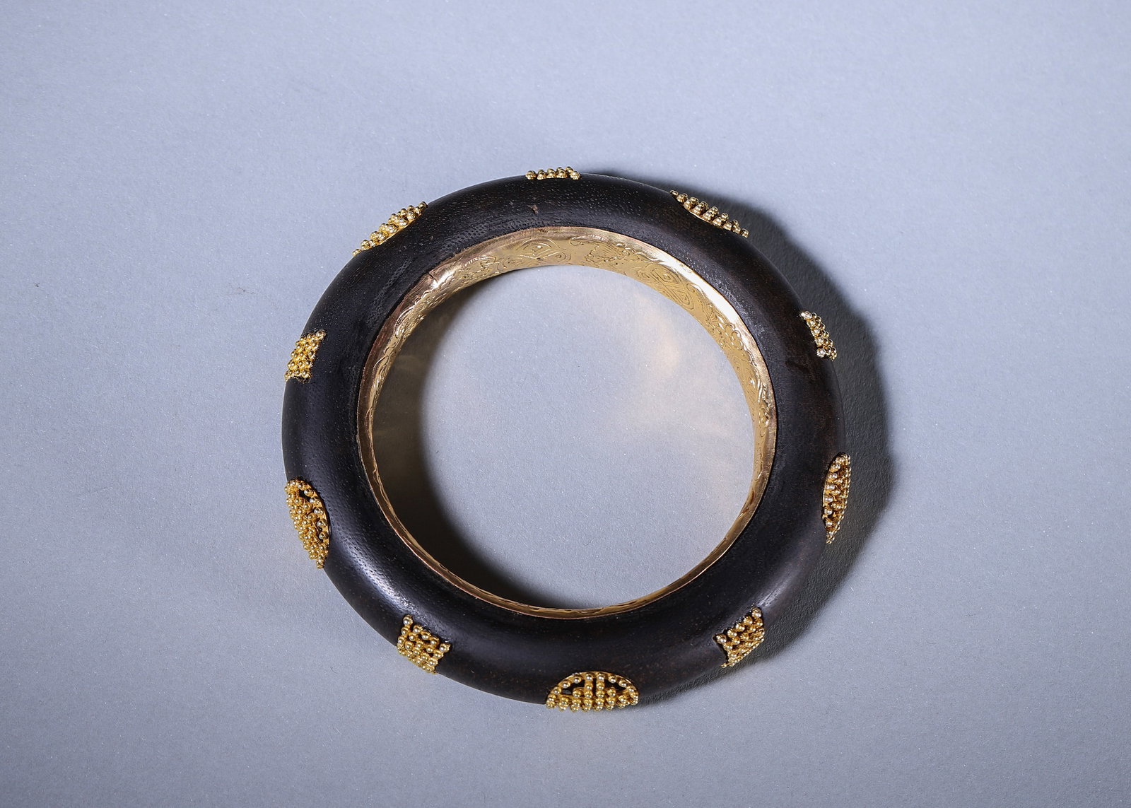 Qing Dynasty,Chenxiang Bangle With Gilded Lining And Gold Granulation Shou Character Motif, Marked: Crafted with chenxiang agarwood core, the inner lining is gilded and engraved with auspicious patterns, bearing the mark "Imperial Manufacture of Qianlong??. The outer surface is decorated with gold g