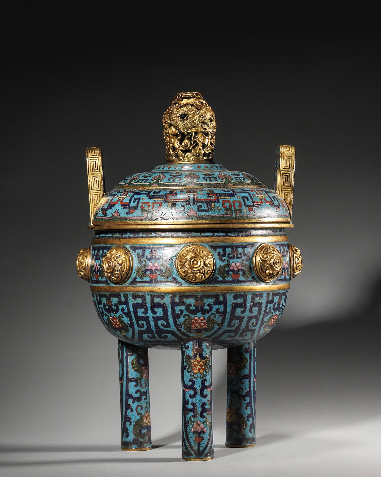 Gilt-Bronze Cloisonne Archaistic Tripod Censer, Qianlong Mark, Qing Dynasty: Archaistic tripod censer with upright handles, openwork gilt dragon finial, gilt bosses, cloisonne archaic beast-mask patterns, bearing Qianlong Nianzhi mark, imperial ritual incense burner.D21cm (8.2