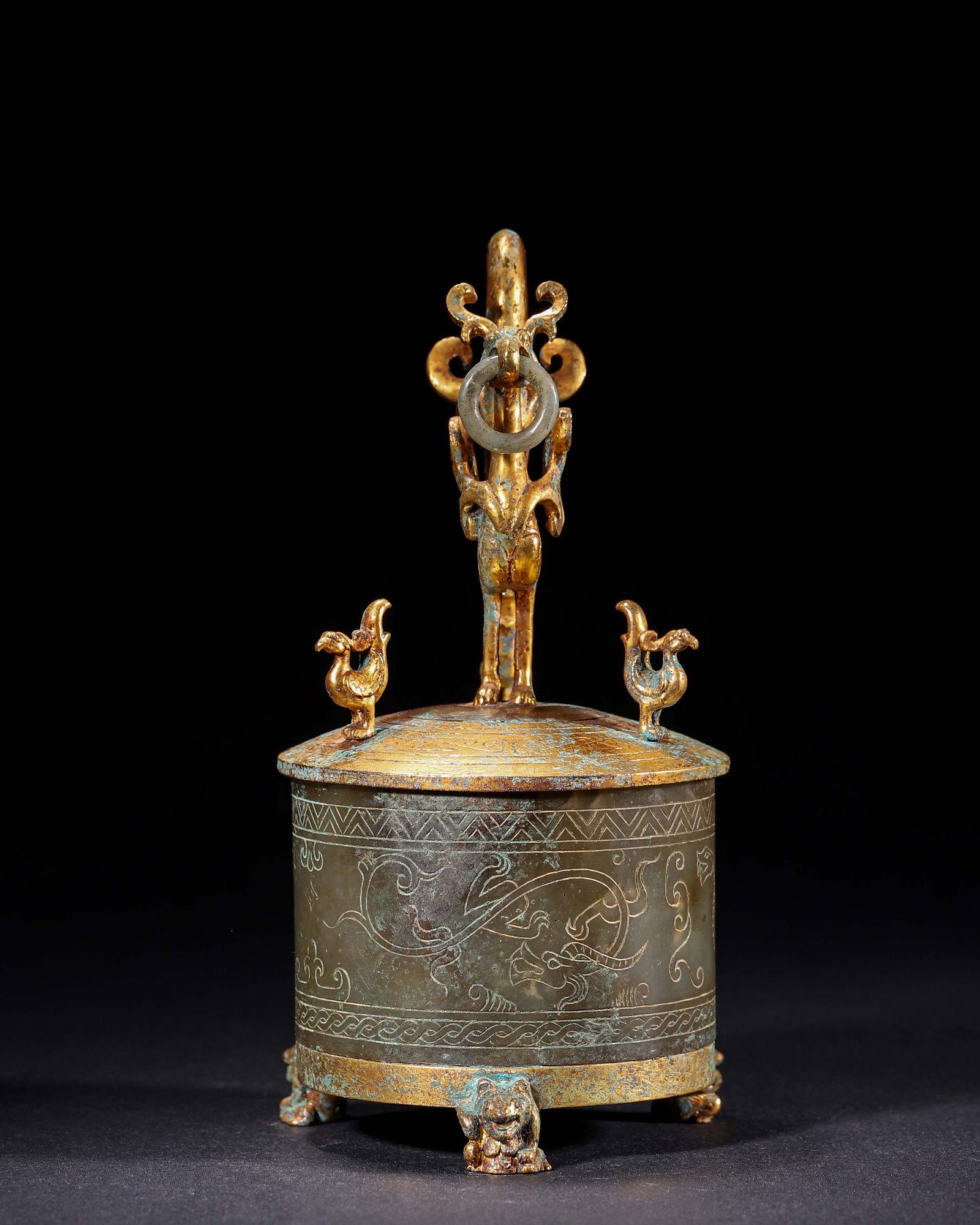 Han Dynasty, Jade Zhi Gilt With Vermilion Bird Knob And Beast Feet: This vessel has a cylindrical jade body carved with dragon patterns, gilt base and lid. The lid has a vermilion bird knob and it stands on three beast feet. It was used as an ancient wine vessel or st