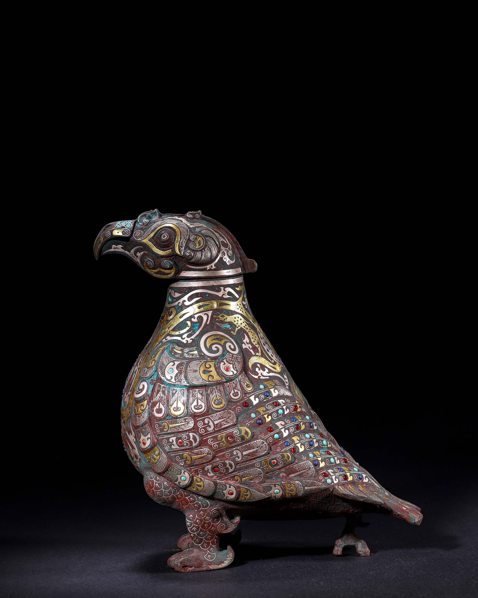 Han Dynasty,Bronze Bird Zun Inlaid With Gold, Silver And Gemstones: The vessel is modelled as a standing sacred bird with a detachable head serving as the lid, bearing clear gold-inlaid inscriptions. Its surface is decorated with gold and silver inlay depicting feathe