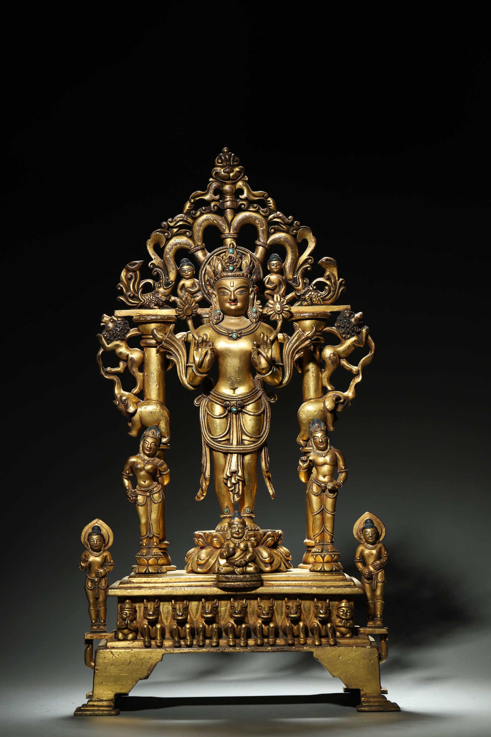 Qing Dynasty, Gilt-Bronze Avalokitesvara Ensemble Statue: A Qing dynasty gilt-bronze Avalokitesvara group statue. Main deity stands on lotus throne with open-work mandorla and multi-tier base, flanked by attendants and mythical beasts. Inlaid stones, double 