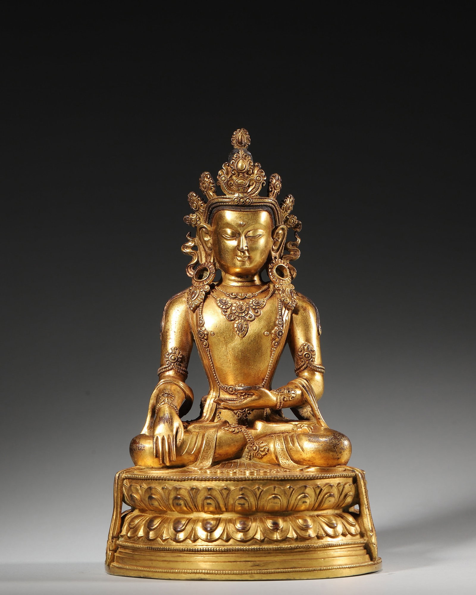 Gilt-Bronze Crowned Shakyamuni Buddha, Qing Period: Gilt-bronze crowned Shakyamuni Buddha in full lotus posture, bhumisparsha mudra, bowl in left hand, ornate bejewelled ornaments, double lotus base engraved with double vajra, Qing Tibetan Buddhist dev