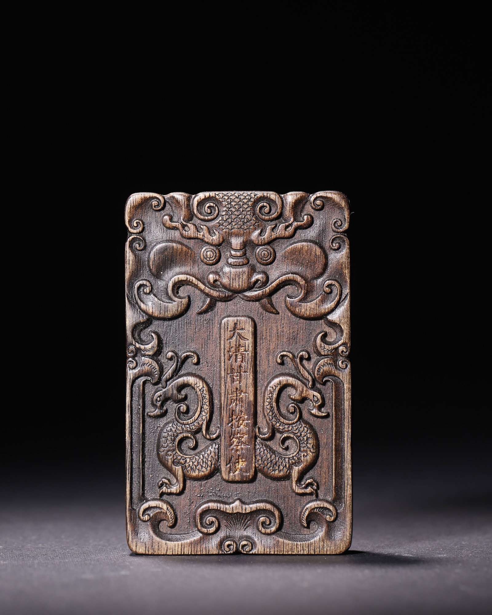 Agarwood Official Token Of Gansu Judicial Commissioner Qing Dynasty: Agarwood official token. Obverse carved beast head and double dragons with inscriptions. Reverse inscribed official title texts. Drilled holes at base, fine carving.Wt 55g (0.12 lb); L 8cm (3.15 in); 