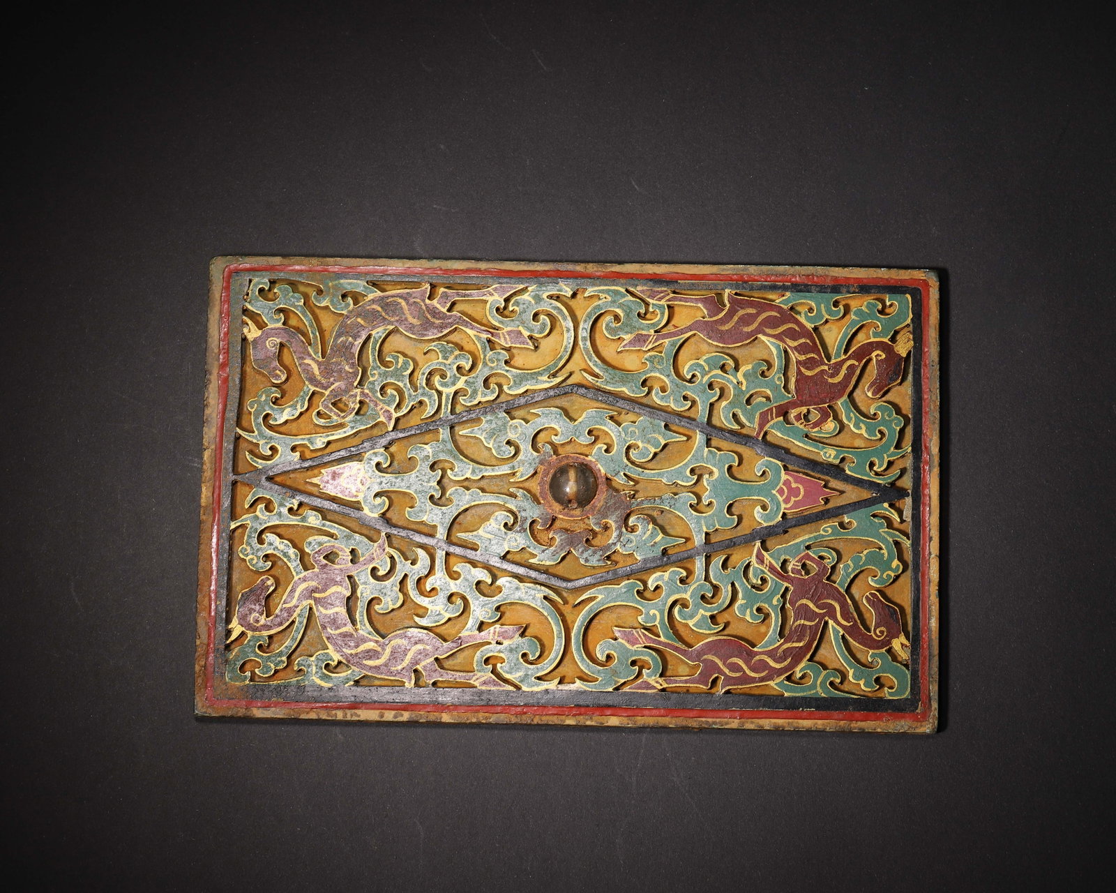 Han Dynasty,Openwork Bronze Plaque With Painted Auspicious Beast Patterns: This rectangular bronze plaque is crafted with openwork carving. Auspicious beasts and scrolling cloud motifs are outlined in gold, red and green pigments, with an inlaid bead ornament at the centre. 