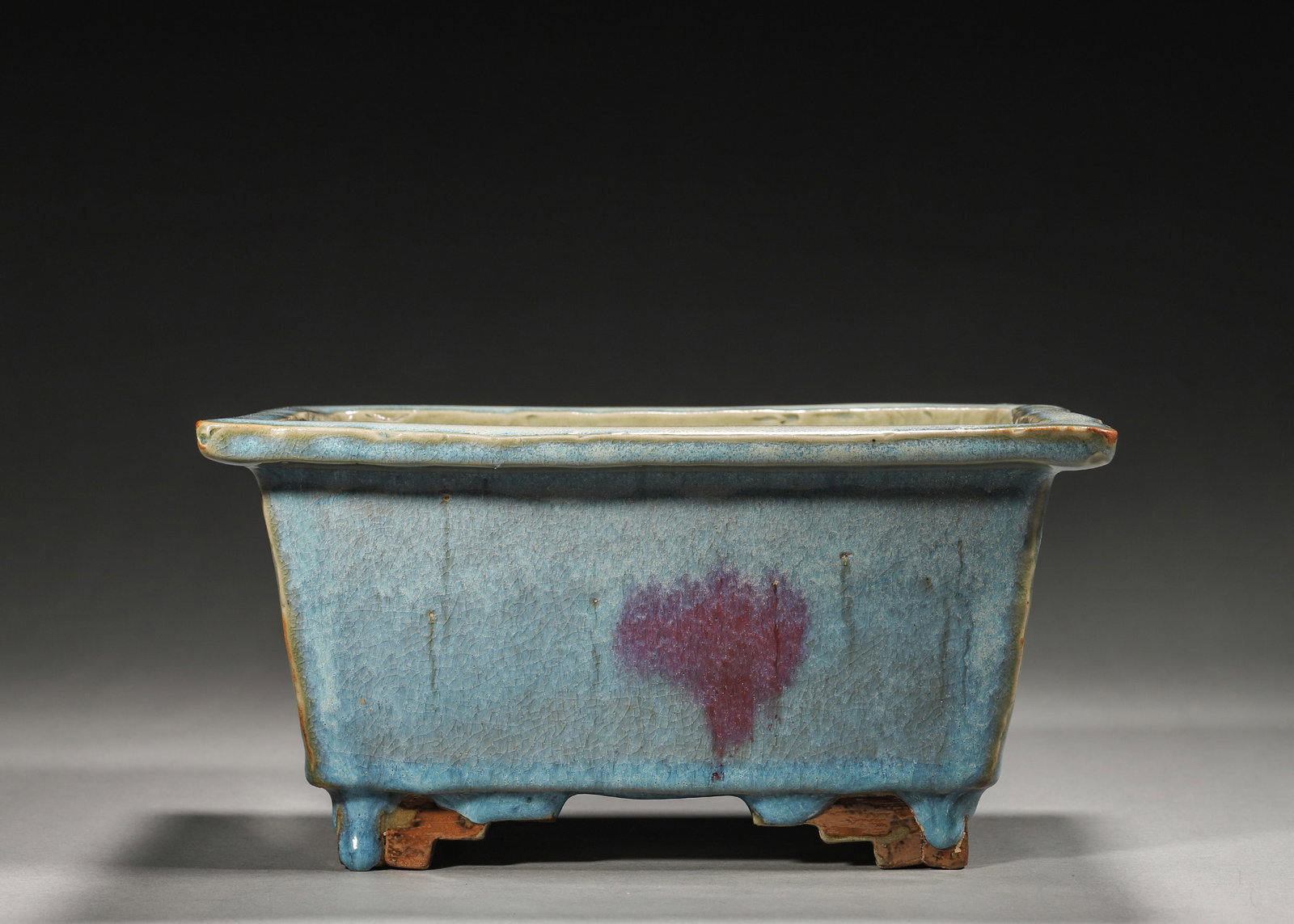 Jun Kiln Sky-Blue Glazed Square Flower Pot With Purple Splashes (Yuan,1271-1368): Square shape with flared rim, supported by four feet. Sky-blue glaze with purple kiln-change splashes, crackled glaze surface. Thick body, exposed base, a Jun-yao display vessel of Yuan dynasty.L 24cm