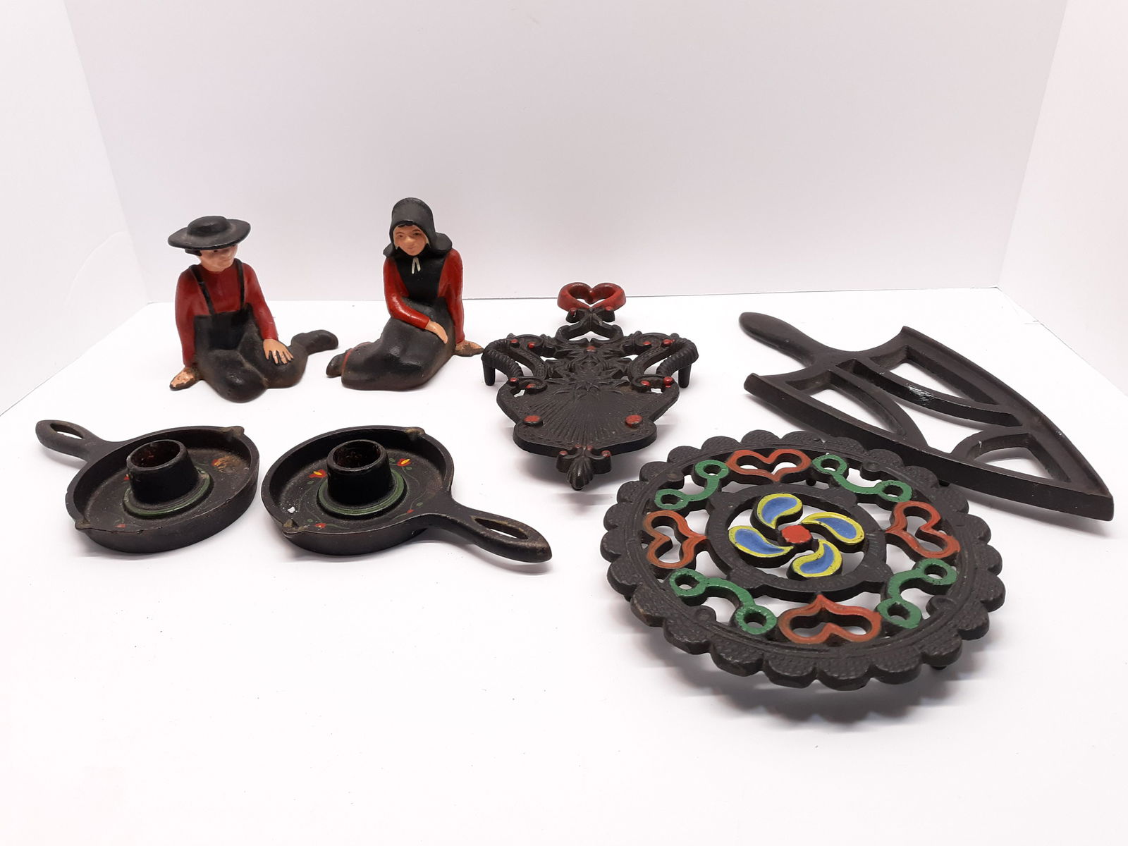 Cast Iron Figures, Trivets and Candle Holders: 2 Early cast iron Amish figures, John Wright trivet, 1948 JHZ cast iron trivet, unsigned cast iron trivet, pair of cast iron candle holders