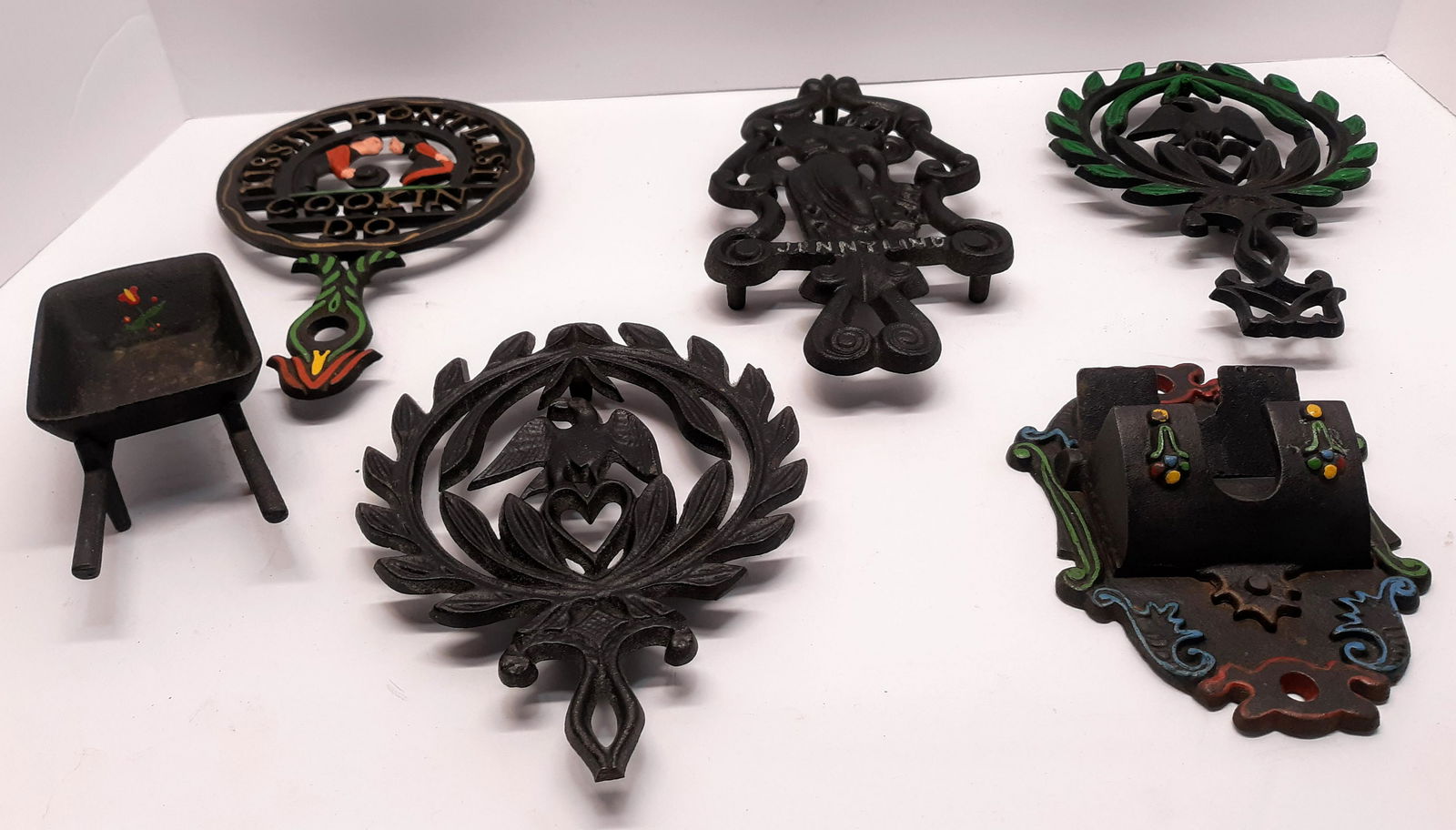 Cast Iron Trivets, Match Safe and Wheelbarrow: J.Z.H. 1945 Jenny Lind cast iron trivet, Wilton Amish boy & girl cast iron trivet, 2 piece cast iron wheelbarrow, cast iron match safe, trivet marked 266, unmarked cast iron trivet