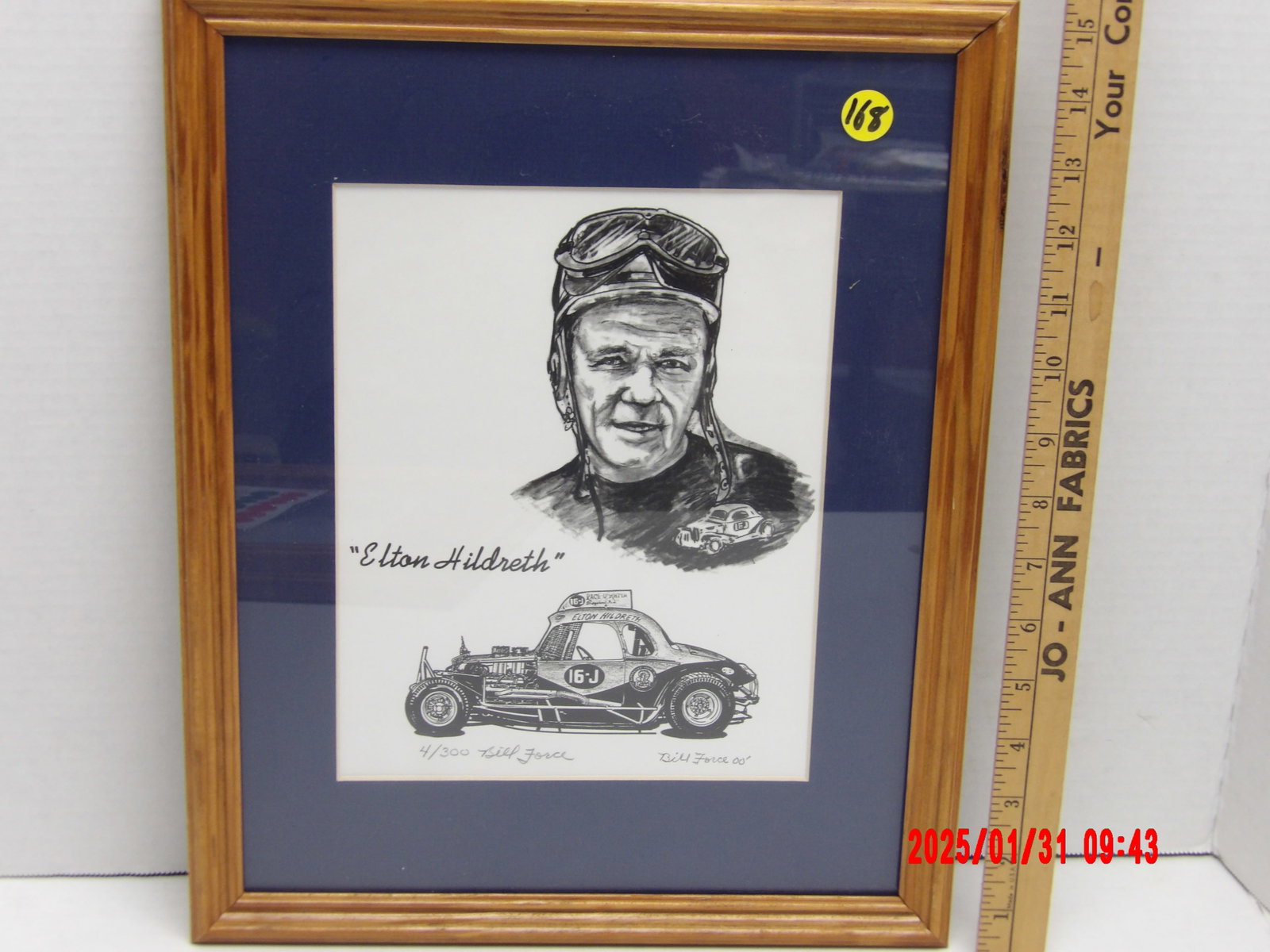 Framed Limited Edition Autograph "Elton Hildreth" Racing Caricature by Bill Force: This framed black and white limited-edition print is a tribute to Elton Hildreth, a respected figure in stock car racing. The print is set in a wooden frame with a natural finish, accented by a dark b