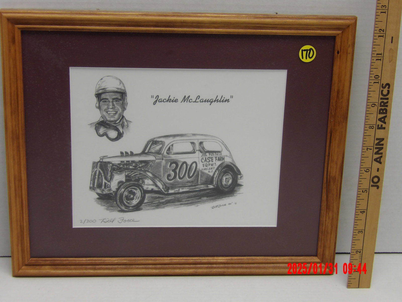 Framed Limited Edition Autograph "Jackie McLaughlin" Racing Caricature by Bill Force: This black and white limited edition print is a tribute to Jackie McLaughlin, a well-known stock car driver. The print is enclosed in a wooden frame with a natural finish, accompanied by a dark maroon