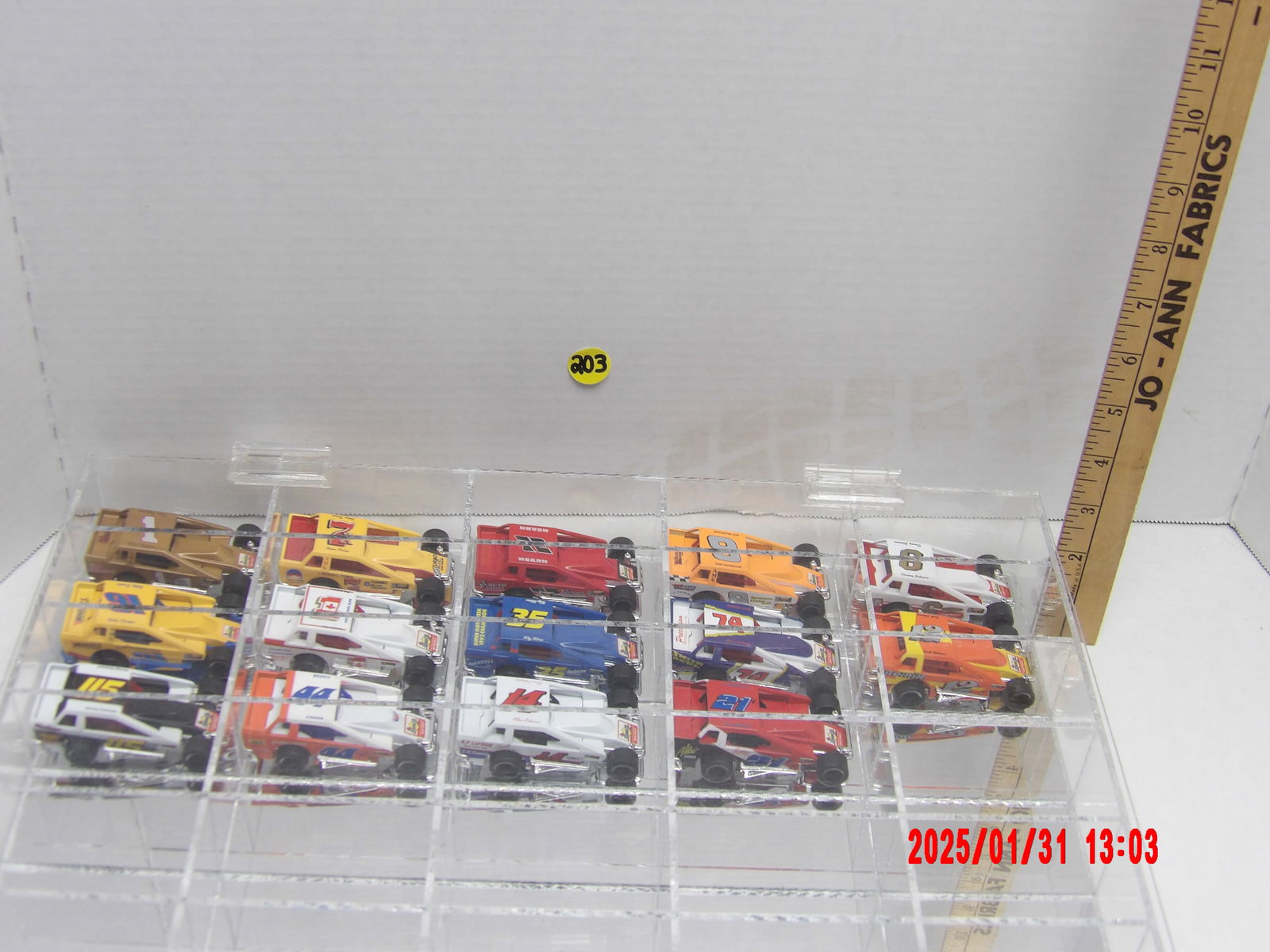 Collection of Miniature Modified Dirt Track Race Cars in Clear Display Case: This lot features a collection of 14 miniature modified dirt track race cars stored in a clear plastic display case with individual compartments. These die-cast or plastic racing models showcase vario