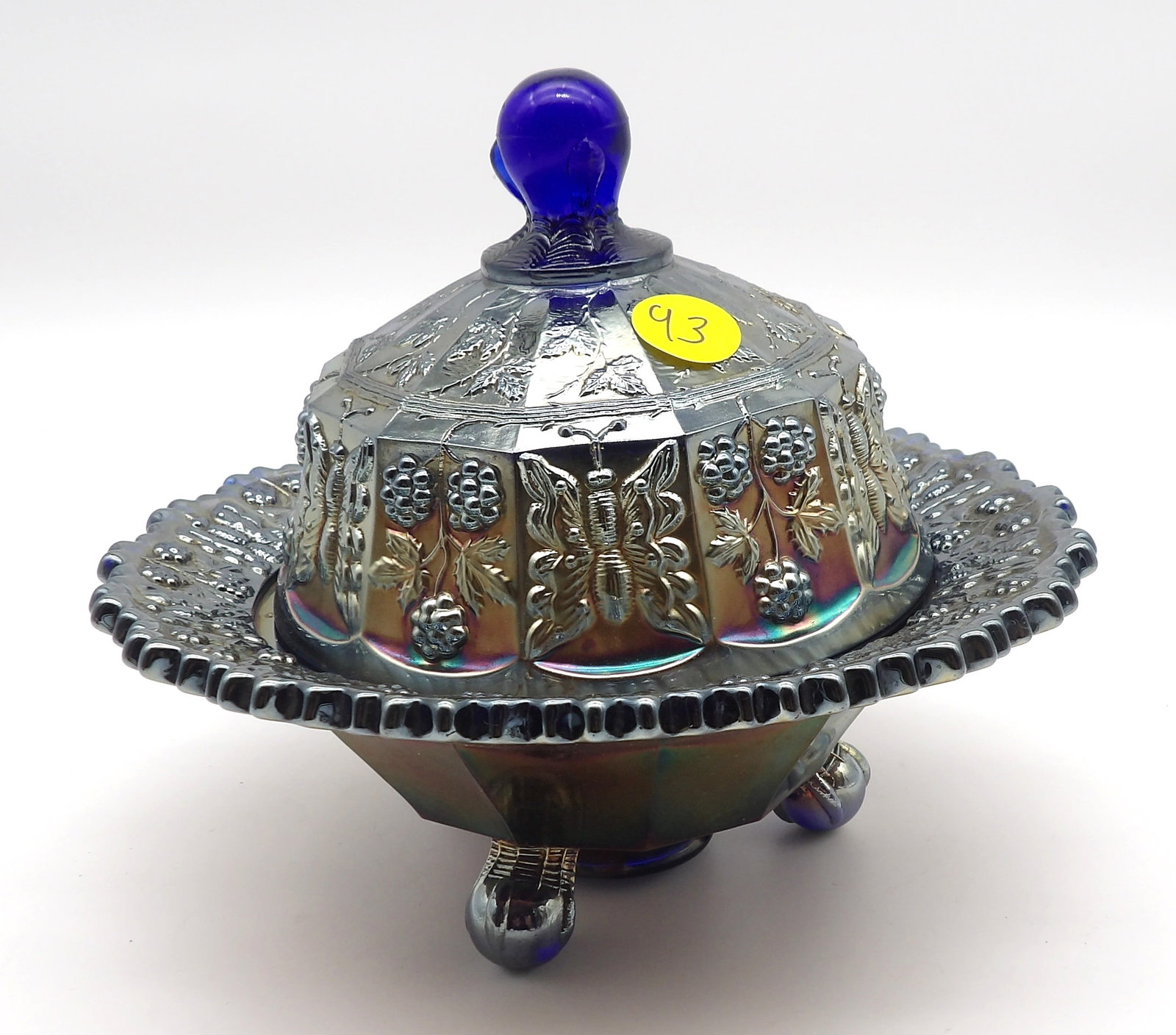 Grape and Cable with Butterfly Electric Blue Glass Covered Butter Dish by Northwood: This striking covered butter dish by Northwood features the Grape and Cable with Butterfly design, one of the company’s most elaborate and desirable patterns. The dish rests on four ball feet, with 