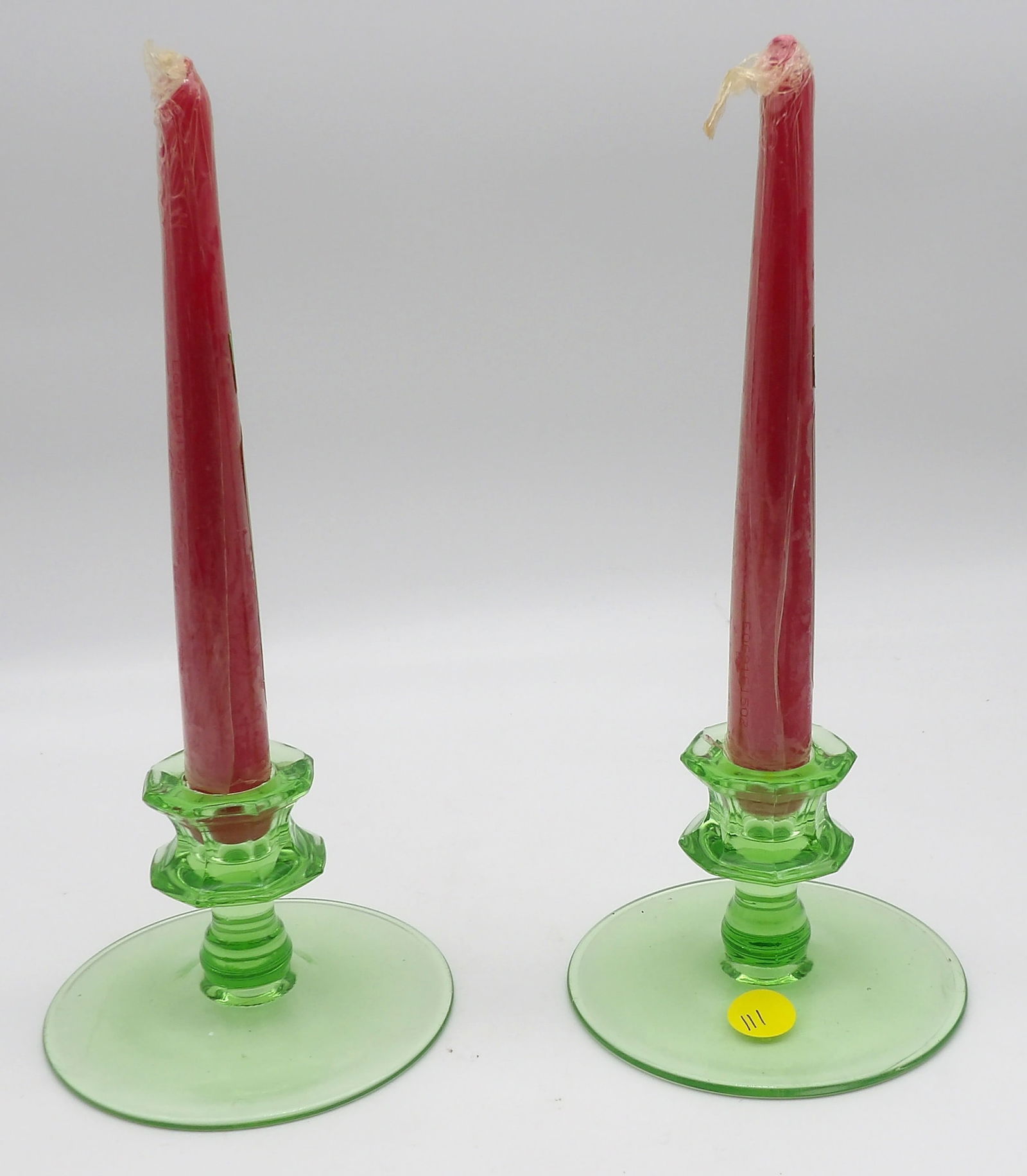 Pair of Uranium Glass Candlesticks with Red Taper Candles: Vintage green uranium glass candlestick holders with red tapers, geometric stem design, glow under UV light. Excellent condition.