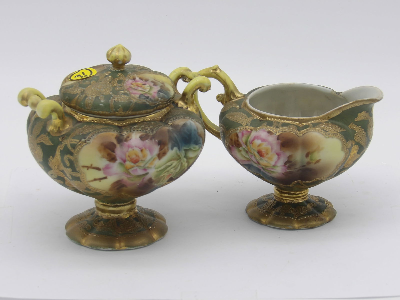 NIPPON PORCELAIN CREAMER & LIDDED SUGAR BOWL: This pair of vintage Nippon porcelain includes a creamer and lidded sugar bowl in ‘moriage’ hand-painted design with raised gold accents.