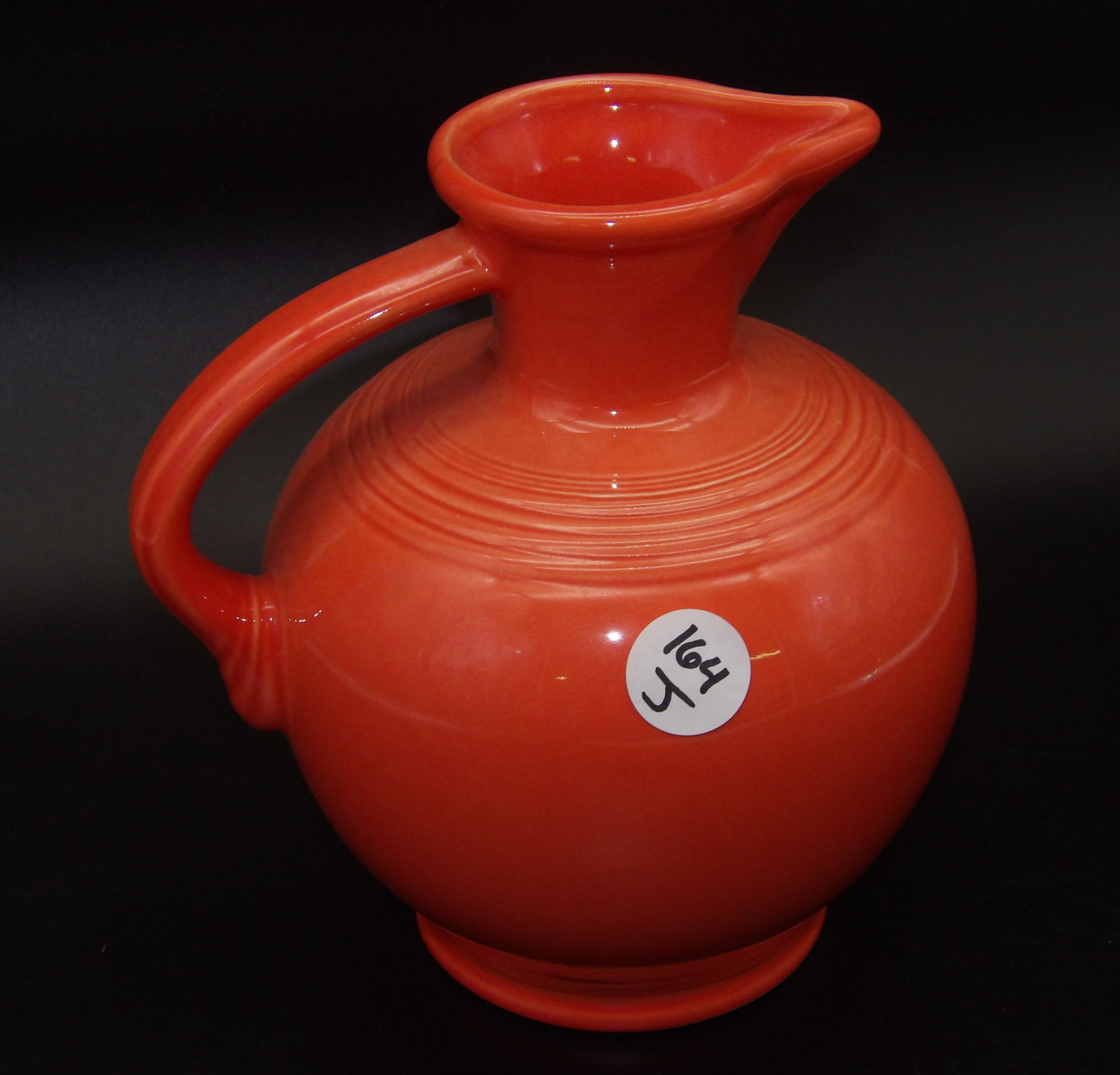 Fiestaware Pitcher: This vintage Fiestaware pitcher comes in Persimmon glaze.Measures:8.5" x 7.5" x 6"