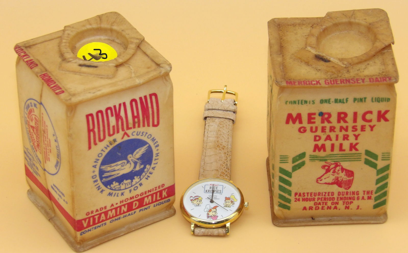 Kellogg's Rice Crispies Watch & Vintage Milk Cartons: This lot includes a Kellogg's Rice Crispies (1990's) watch with genuine Alligator Leather band, along with a pair of vintage plastic milk cartons (Rockland & Merrick Guernsey - 1950's). Measures: 9"